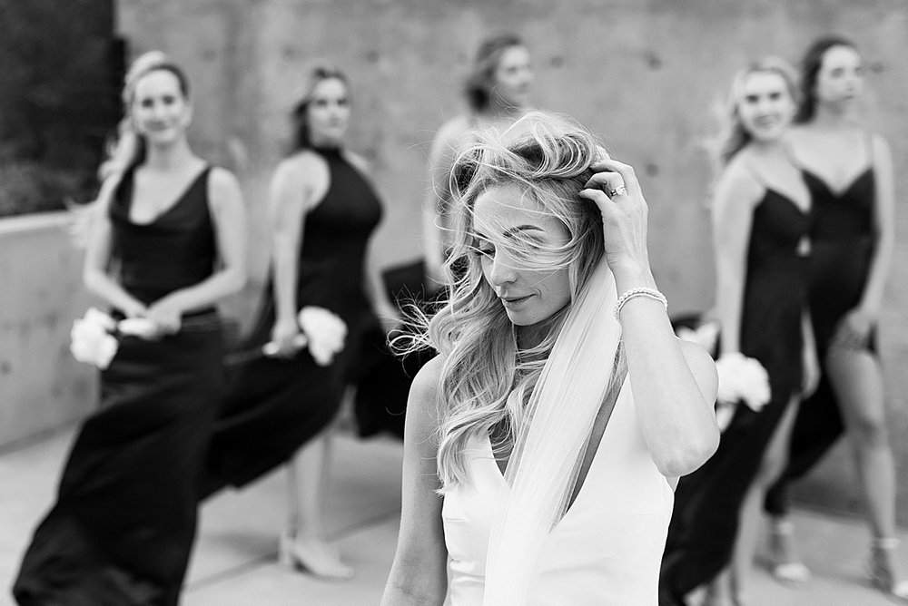Black and white portrait of bridesmaids while wind is whipping through brides hair