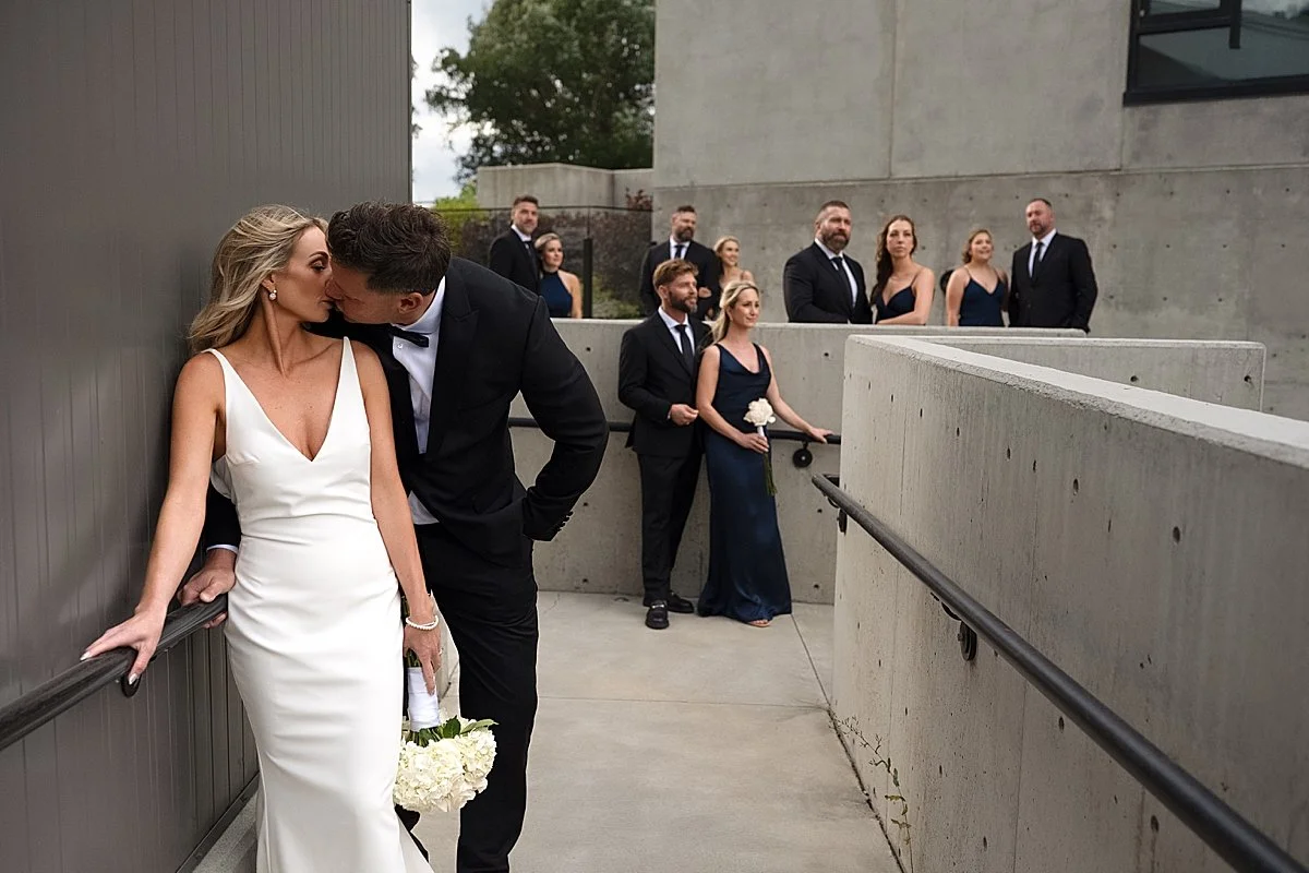 Stylish Wedding Party at Monte Creek Winery while bride and groom share a kiss