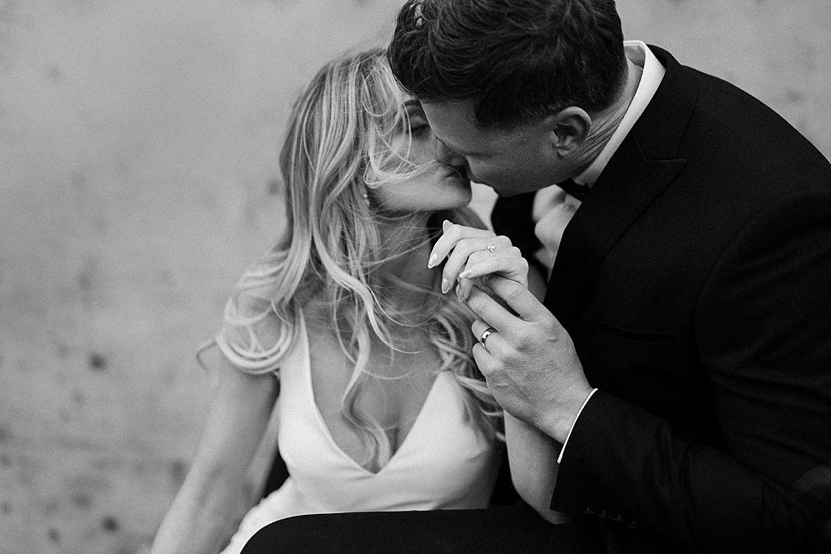 bride and groom share an intimate kiss while holding hands