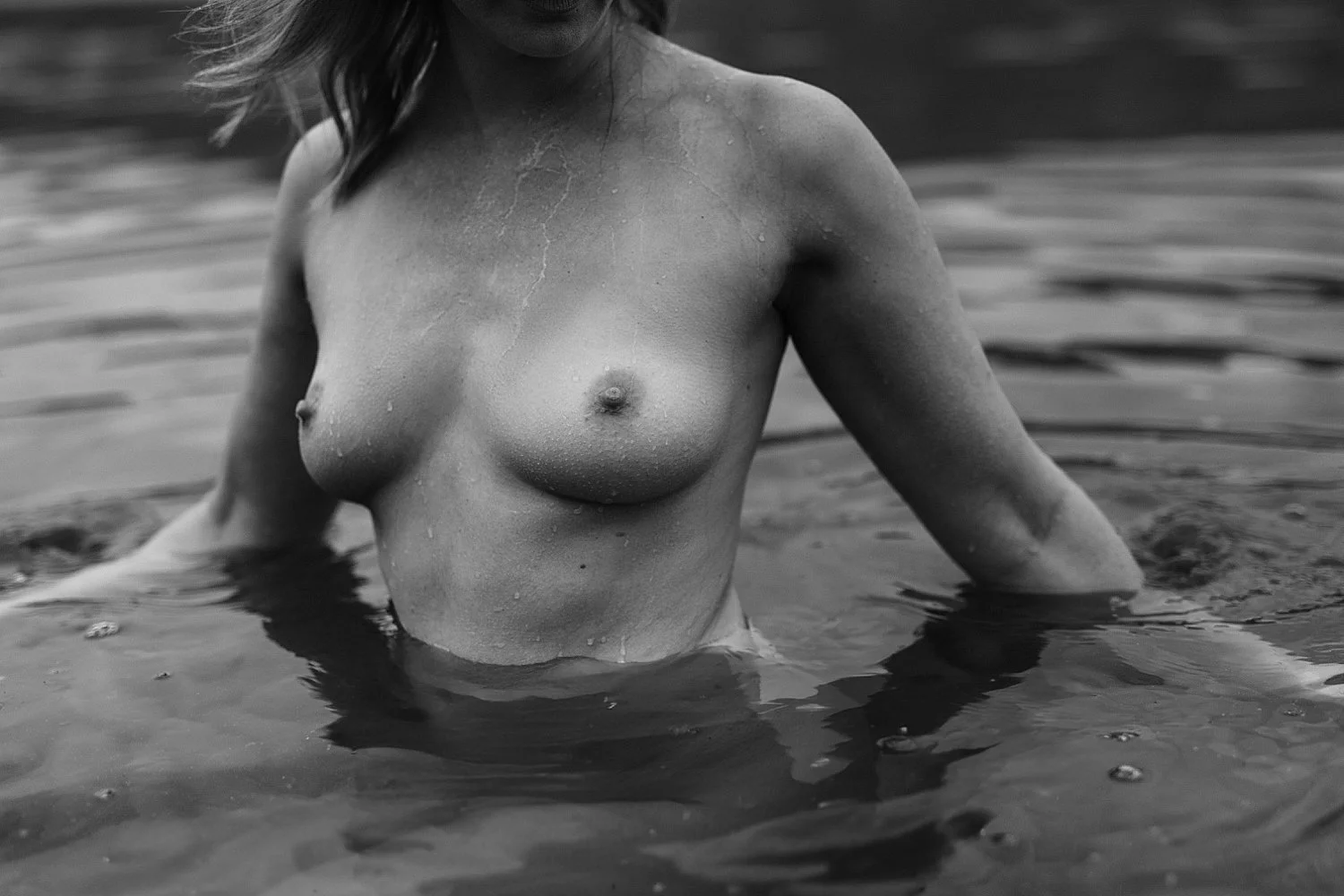 woman nude in water, wet, outdoors in black and white