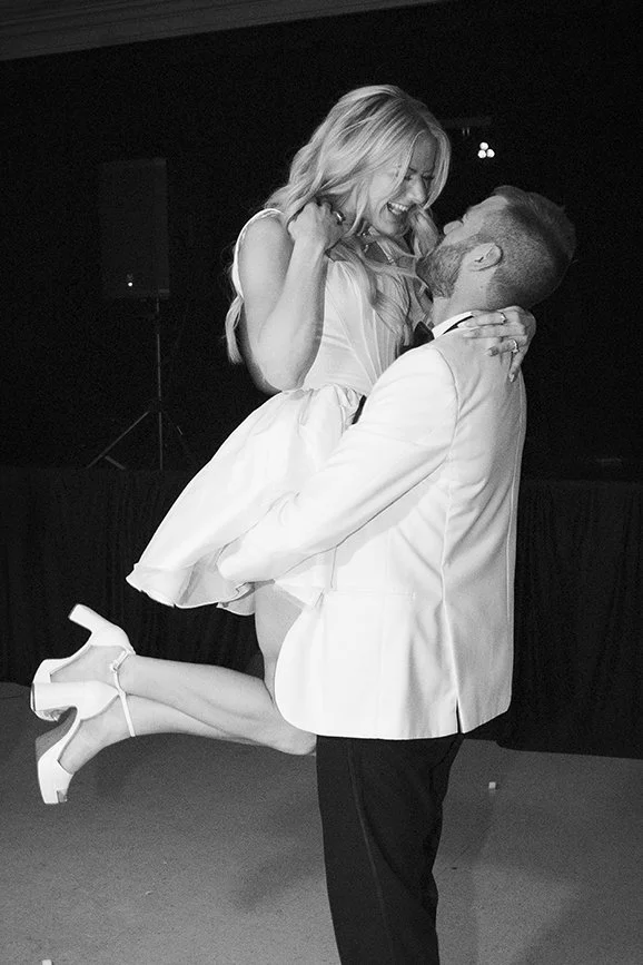 Black and white photo of groom picking up gorgeous bride for private last dance