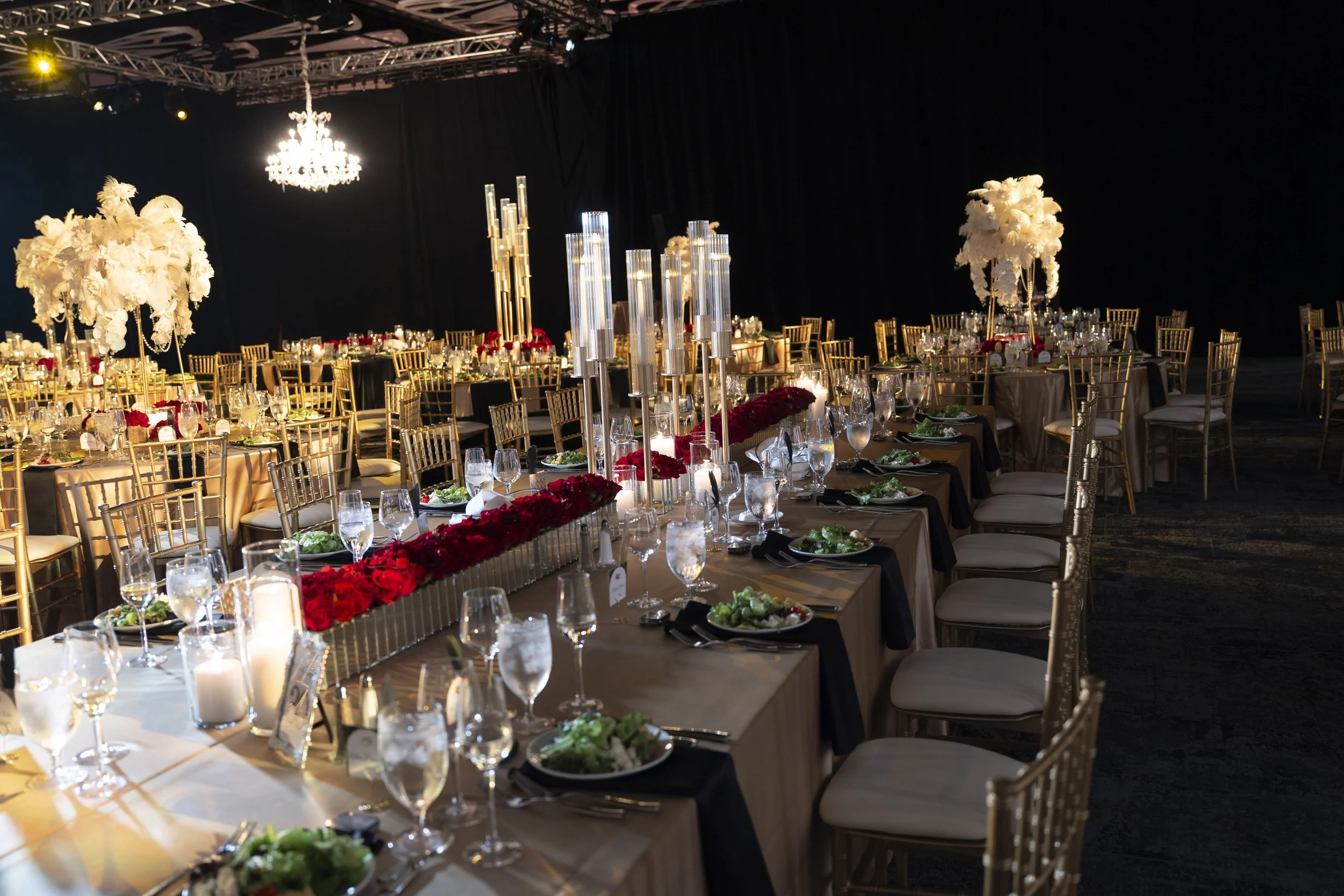 Cleveland Convention Center banquet hall with round tables, gold chairs, tall white floral centerpieces, and clear candle holders, set for a formal event.
