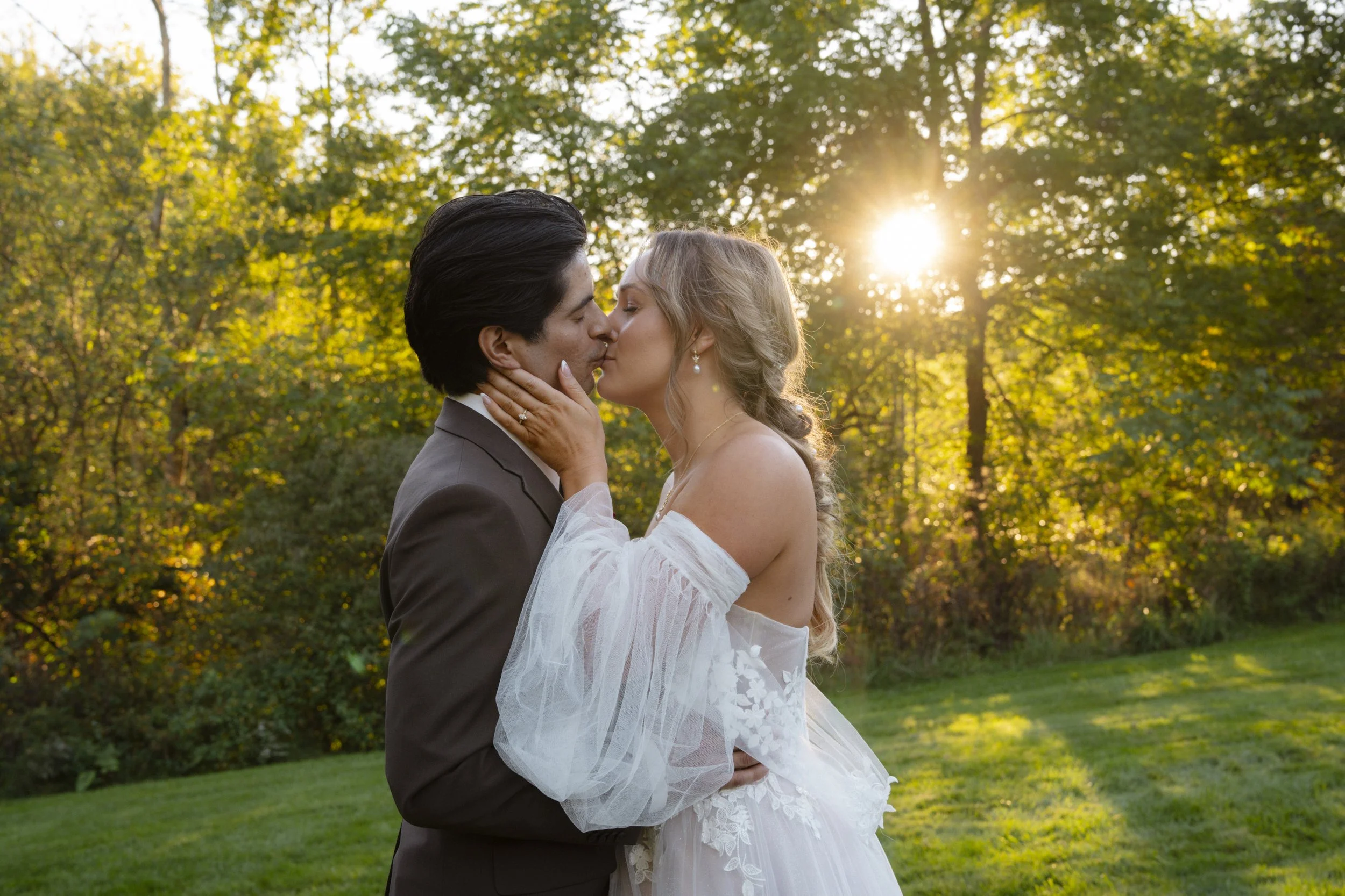Beautiful Wedding couple kissing with a woodsy sunset background
