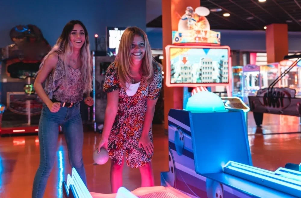 Girlfriends enjoying arcade games at an entertainment center - one of the most fun ideas for double dates.