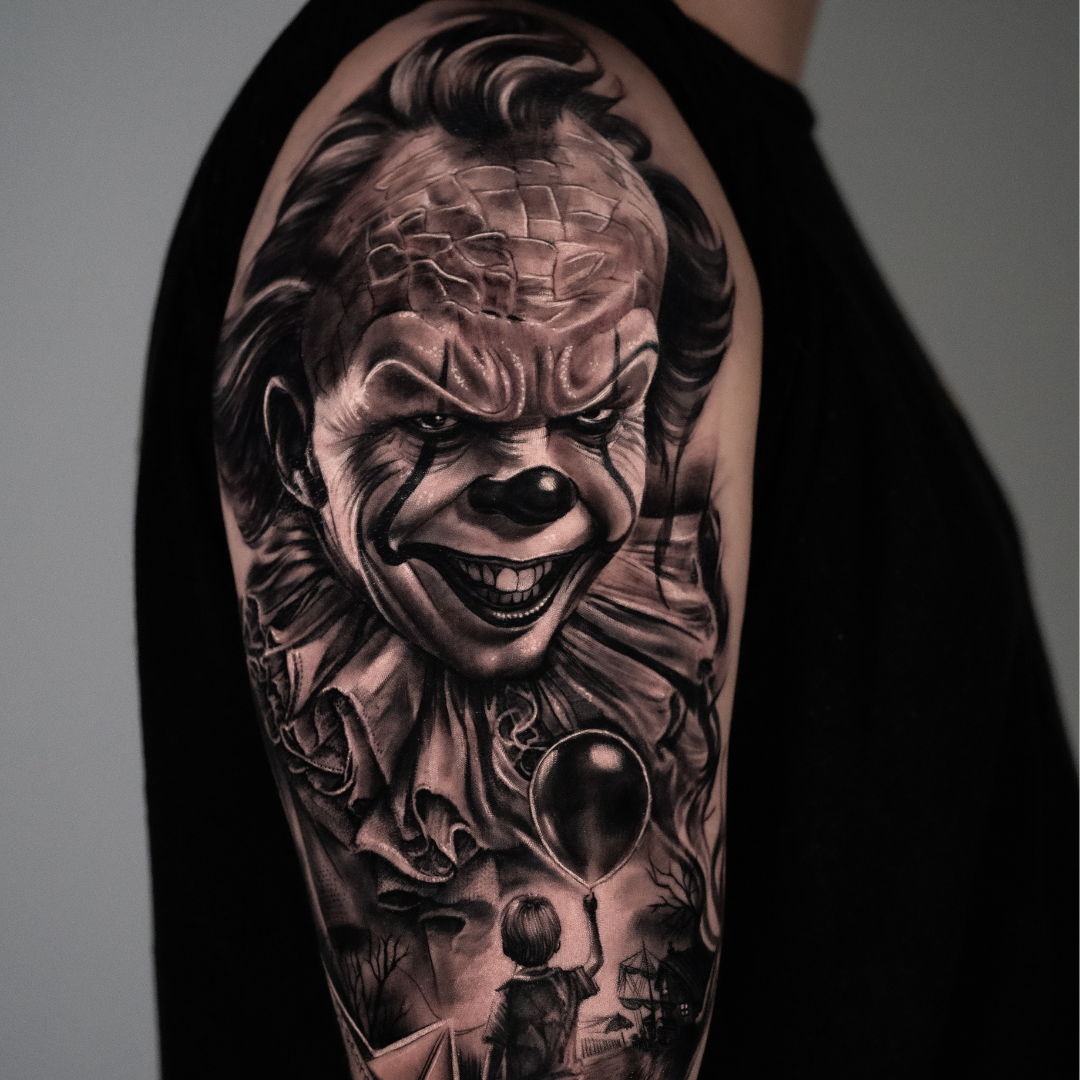 Black and gray tattoo of Pennywise the clown from Stephen King's 'It' on a person's upper arm