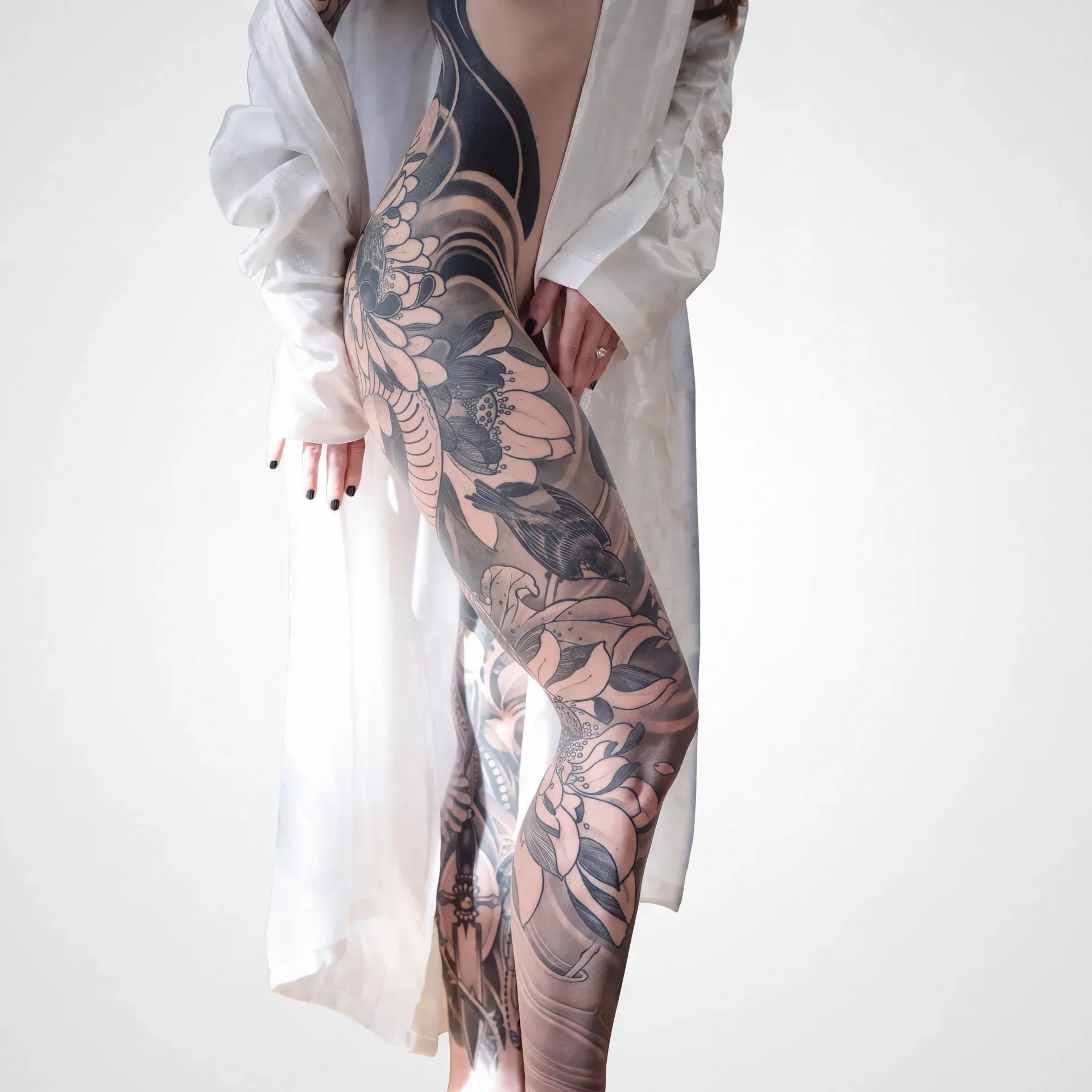 Back view of a woman with a symmetrical black and grey ornamental full body suit from neck through sleeves.