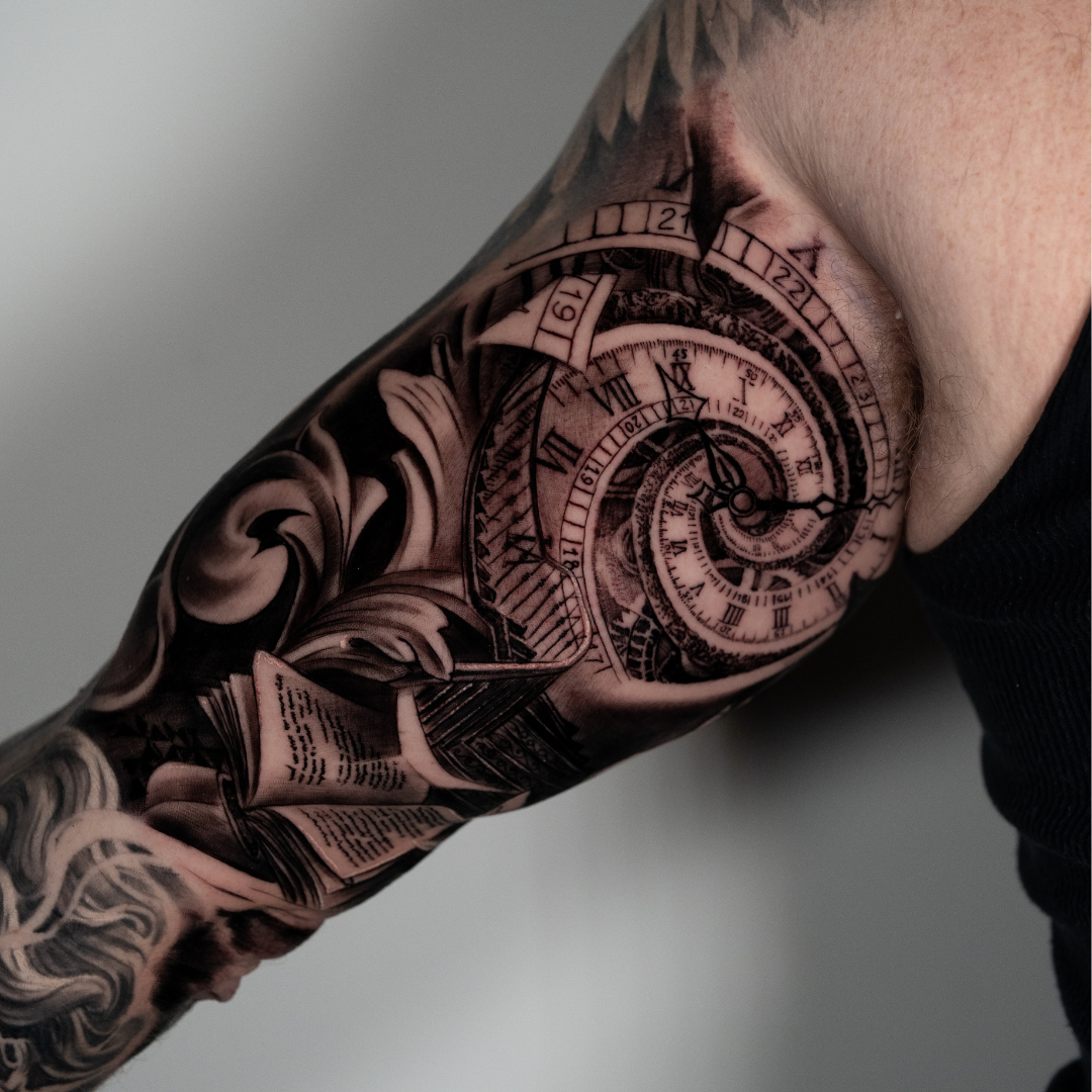 Tattoo of a clock with Roman numerals and spiral design on a person's upper arm and shoulder.