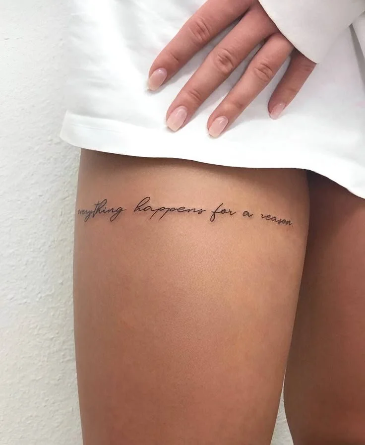 Fine line script thigh tattoo reading “everything happens for a reason”—simple tattoo ideas for women