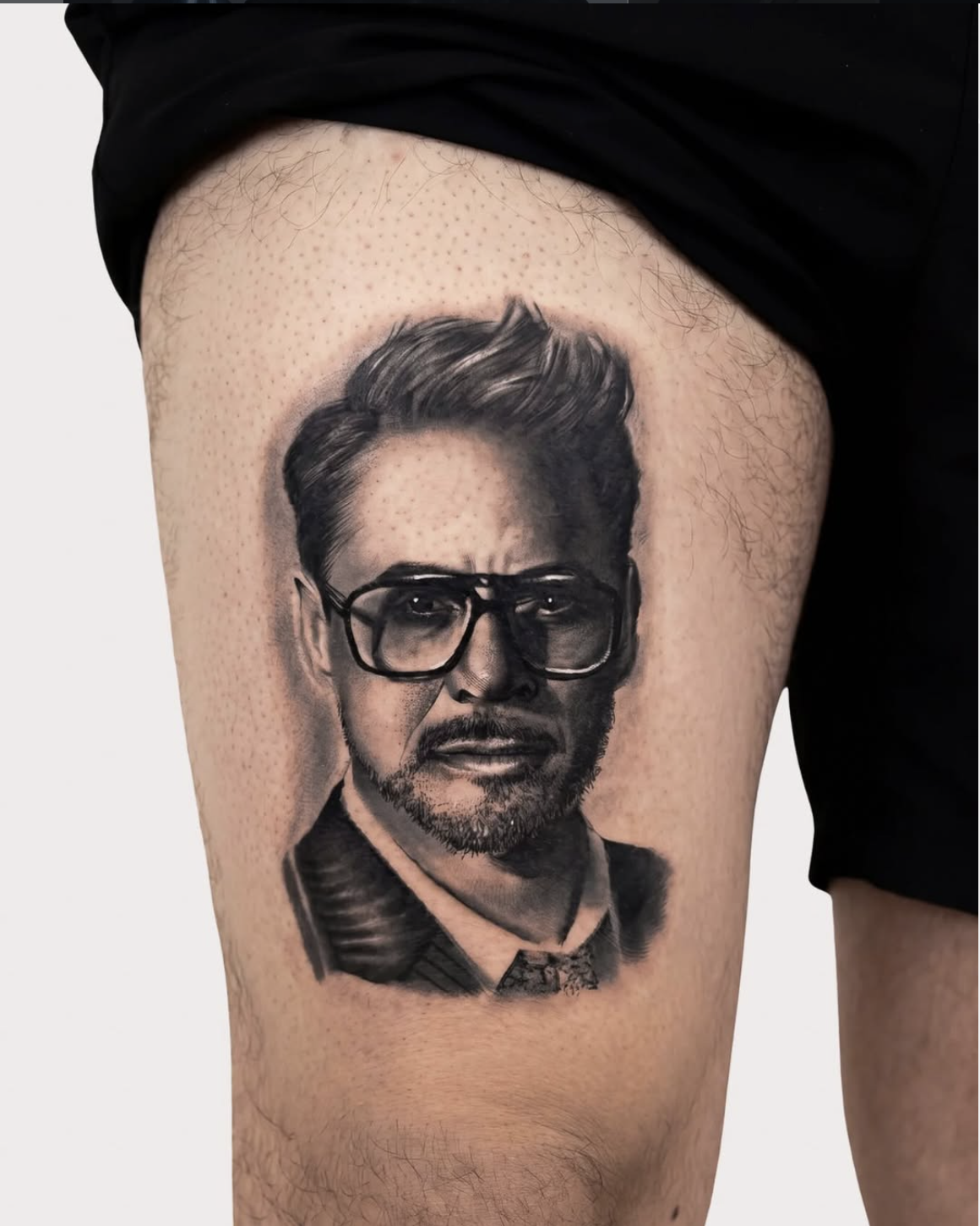 Photorealistic celebrity portrait tattoo of Robert Downey Jr. by Luis Fernandez, Zen Tattoo Studio Oakville. Black and grey realism on thigh — precise likeness, fine detail, true-to-life shading.