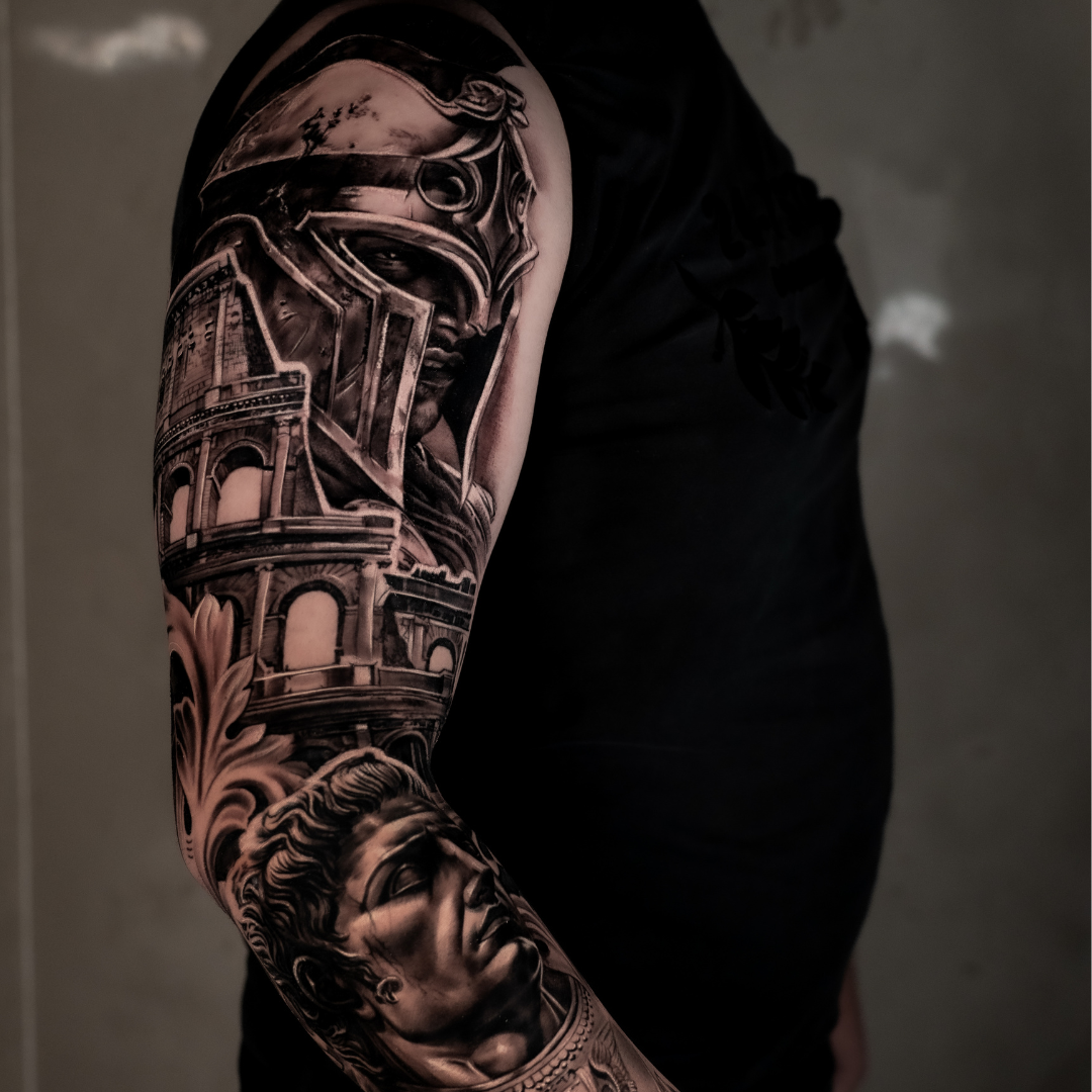 Black and gray tattoo sleeve on a person's arm featuring a gladiator helmet, Roman arches, and a classical statue bust.