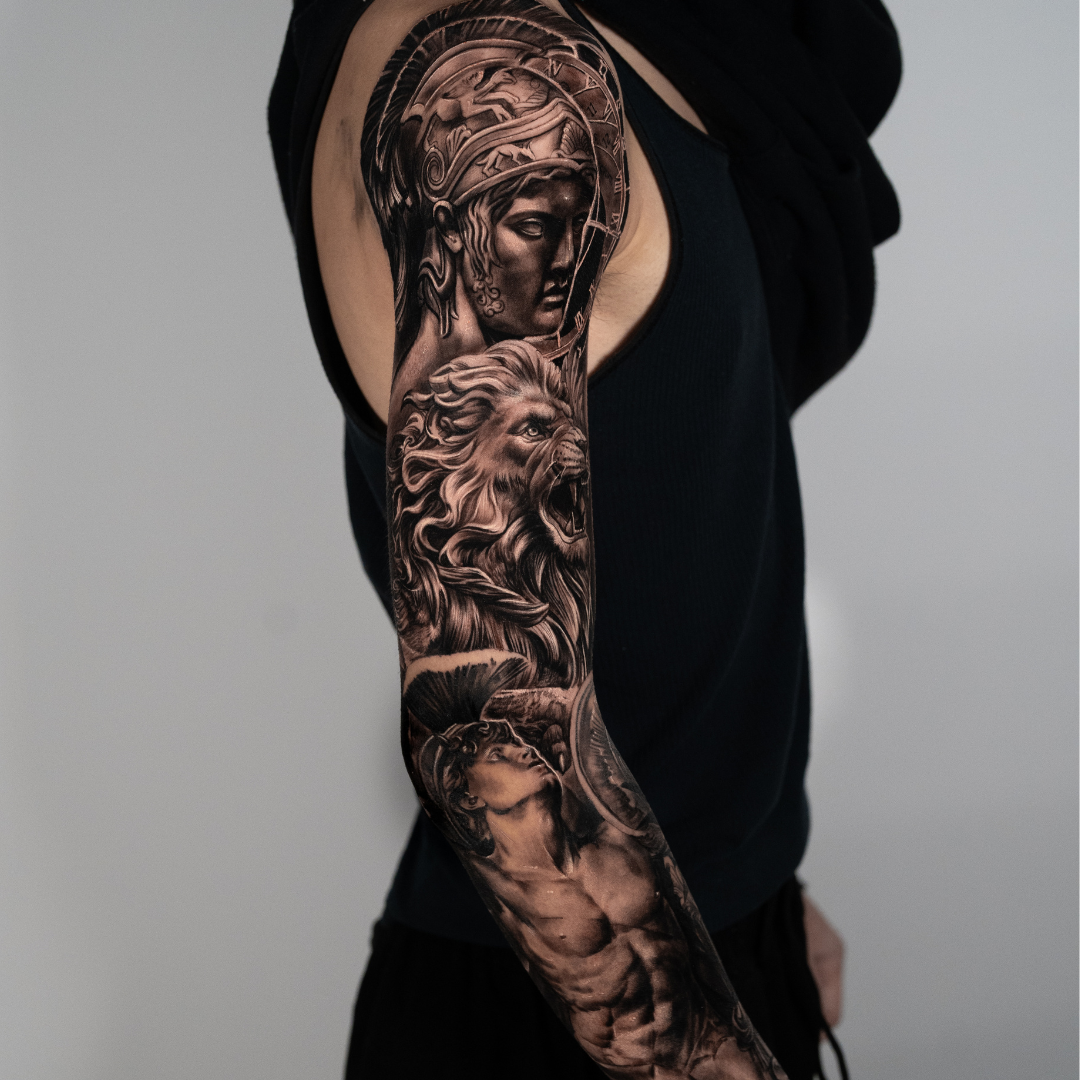 greek mythology arm sleeve Detailed black and gray tattoo sleeve featuring a woman's face with a crown, a roaring lion, and a muscular male figure, on a person's arm.