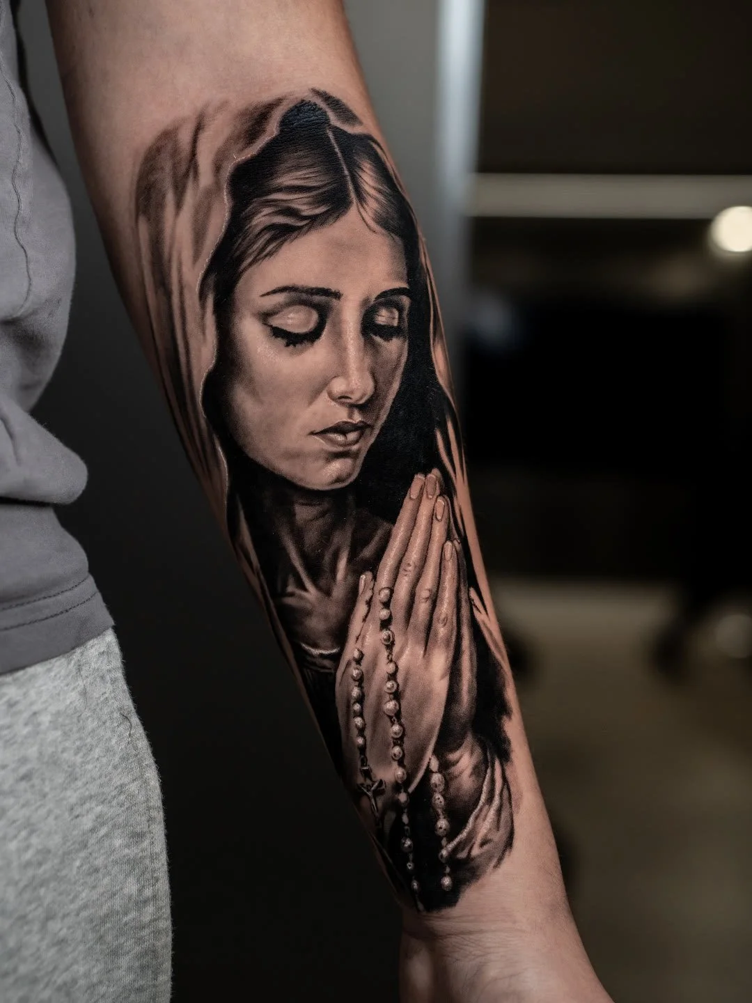 Black and grey realism Virgin Mary rosary portrait tattoo on forearm by Luis Fernandes at Zen Tattoo Studio Oakville
