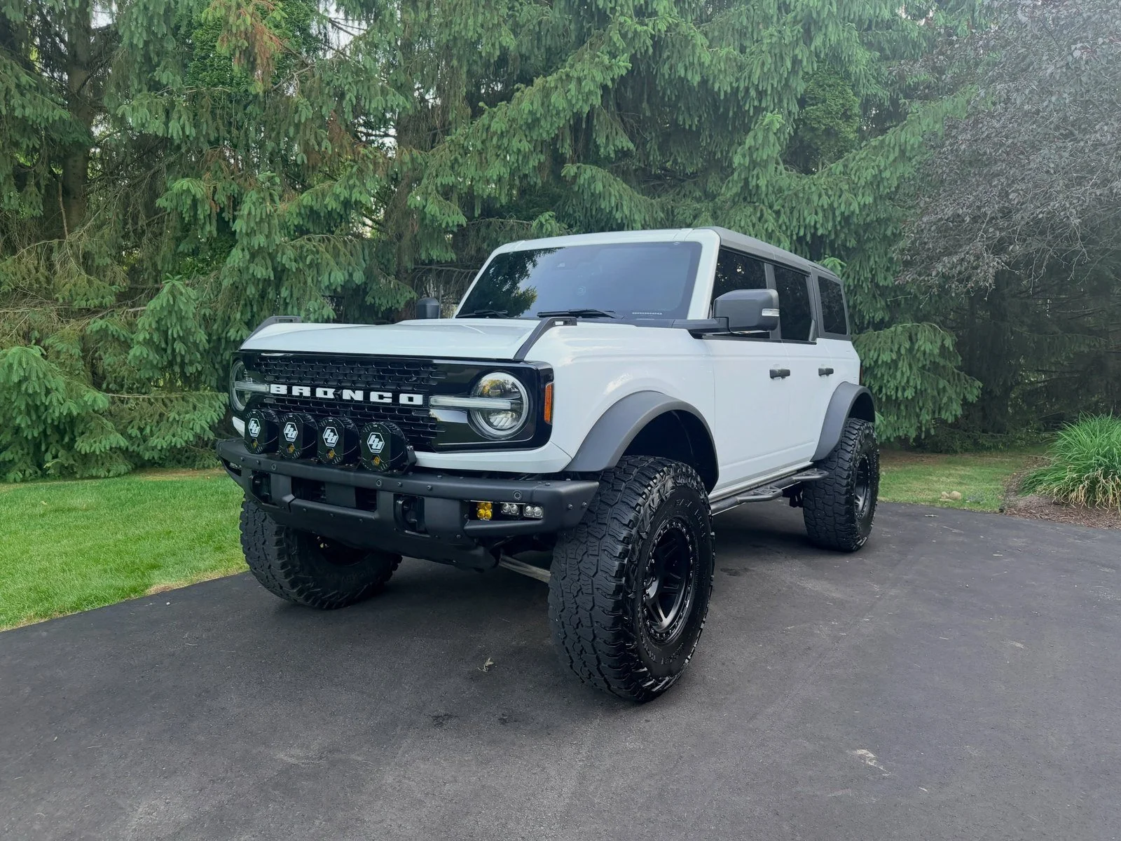 Front end of a white Ford Bronco showing clear headlights after detailing