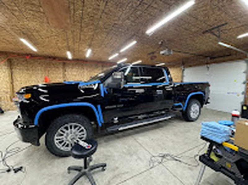 Black pickup taped and prepped for paint correction inside the LCB shop in Howell, MI