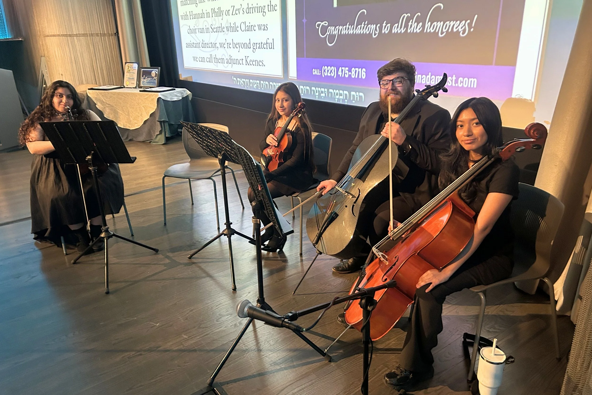 Students Jade, Maya, Teaching Artist Ryan, and Stephany pose for a picture before performing on the auditorium stage.