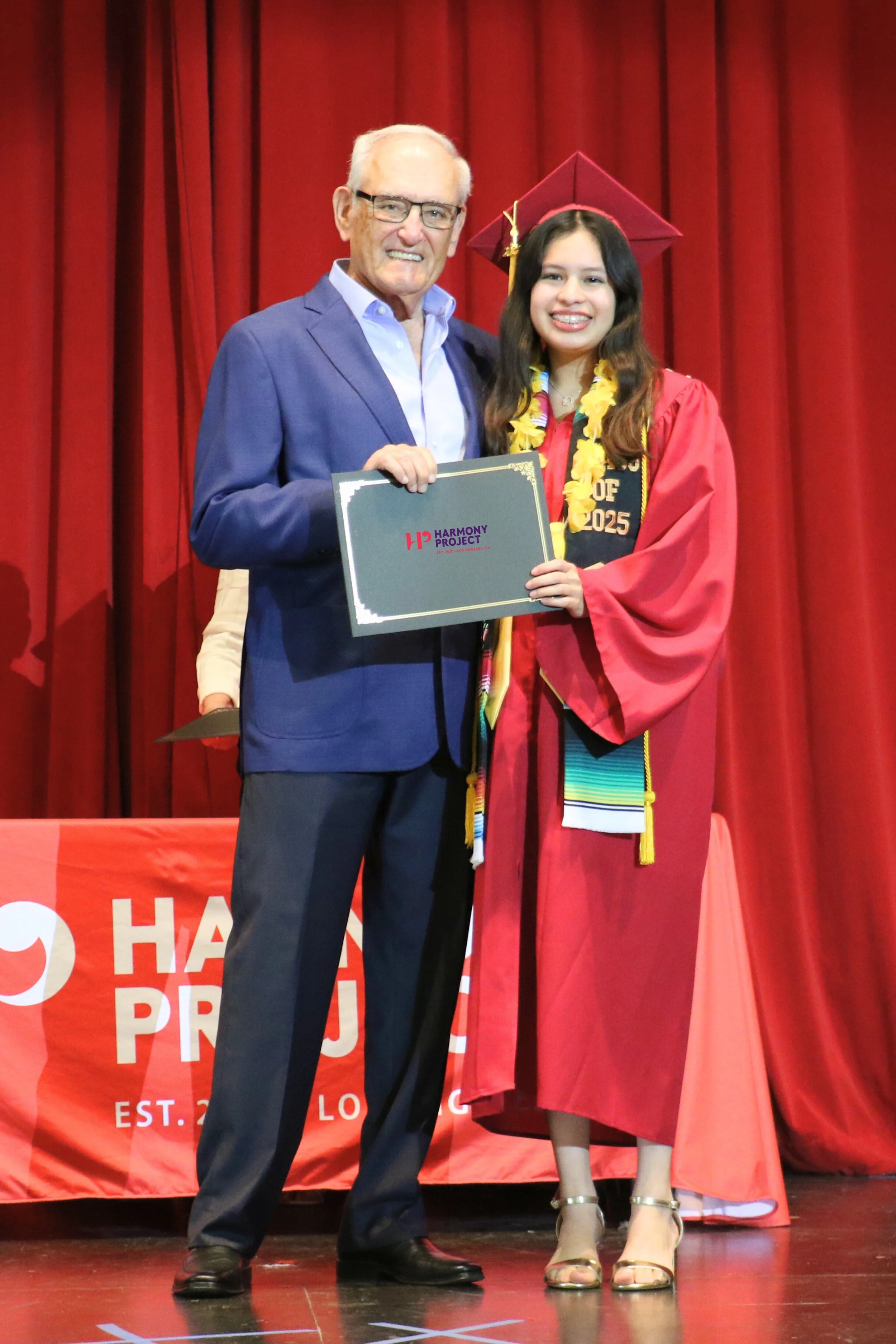 Chairman emeritus posing with student graduate and her Harmony Project diploma.