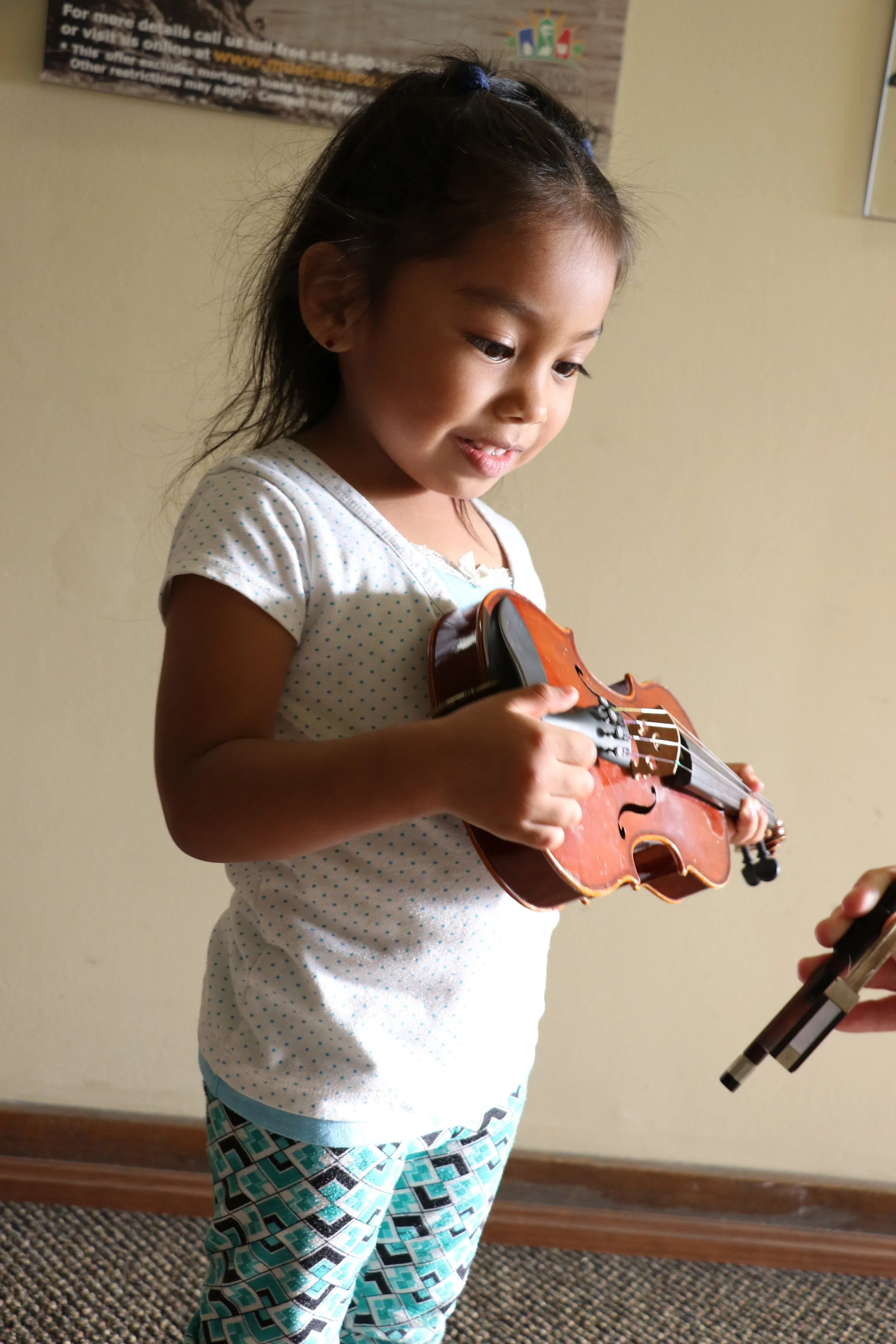 Harmony Project student excited holding onto a baby violin.