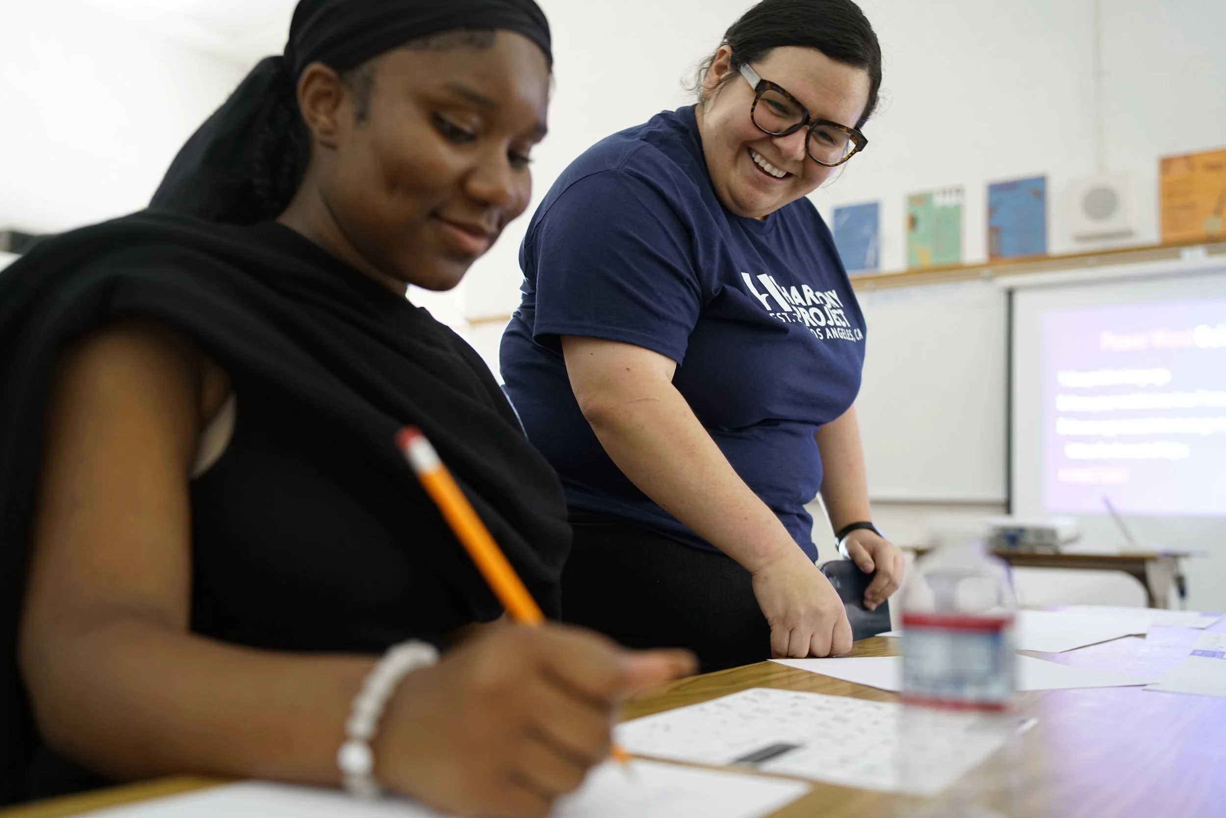 Harmony Project staffer helping student during a journaling workshop.