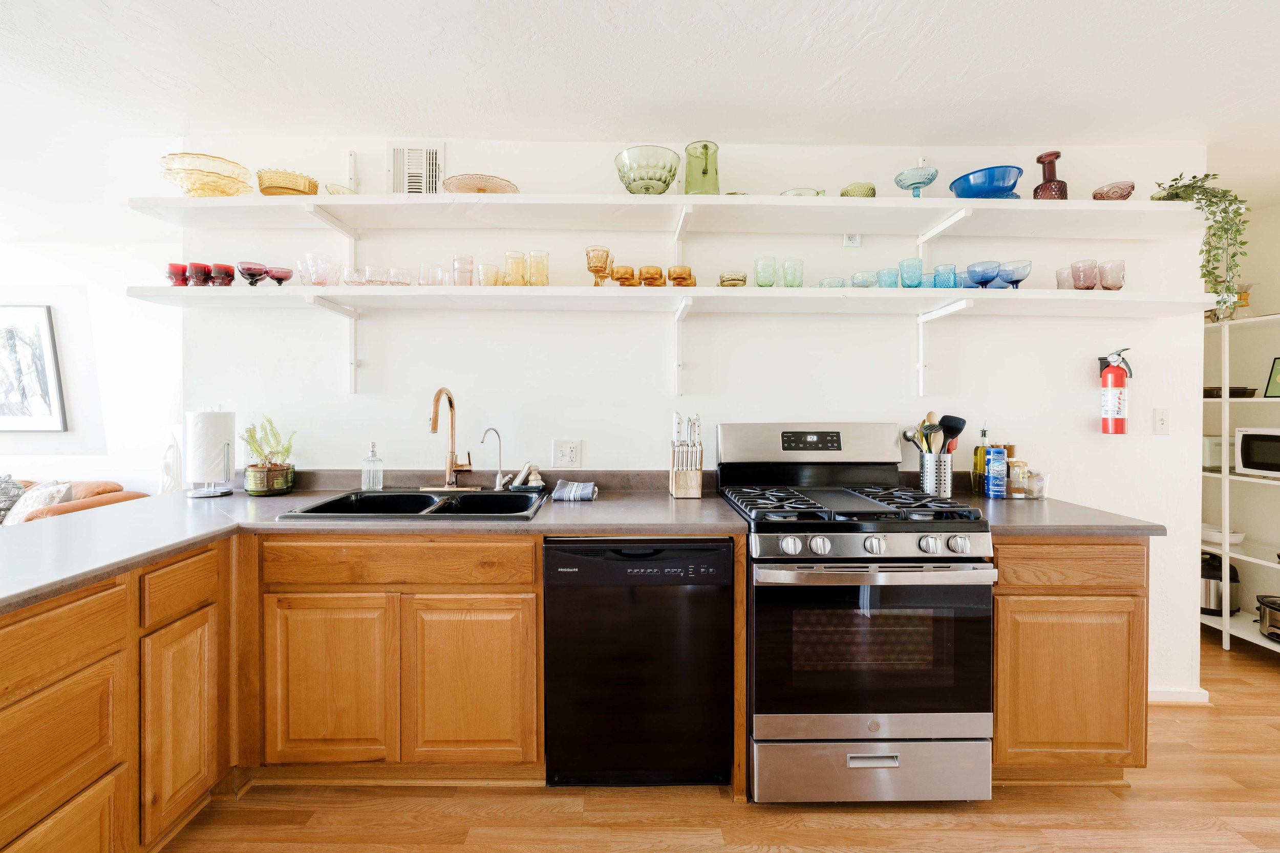The kitchen features color coded kitchenware displayed on open shelves