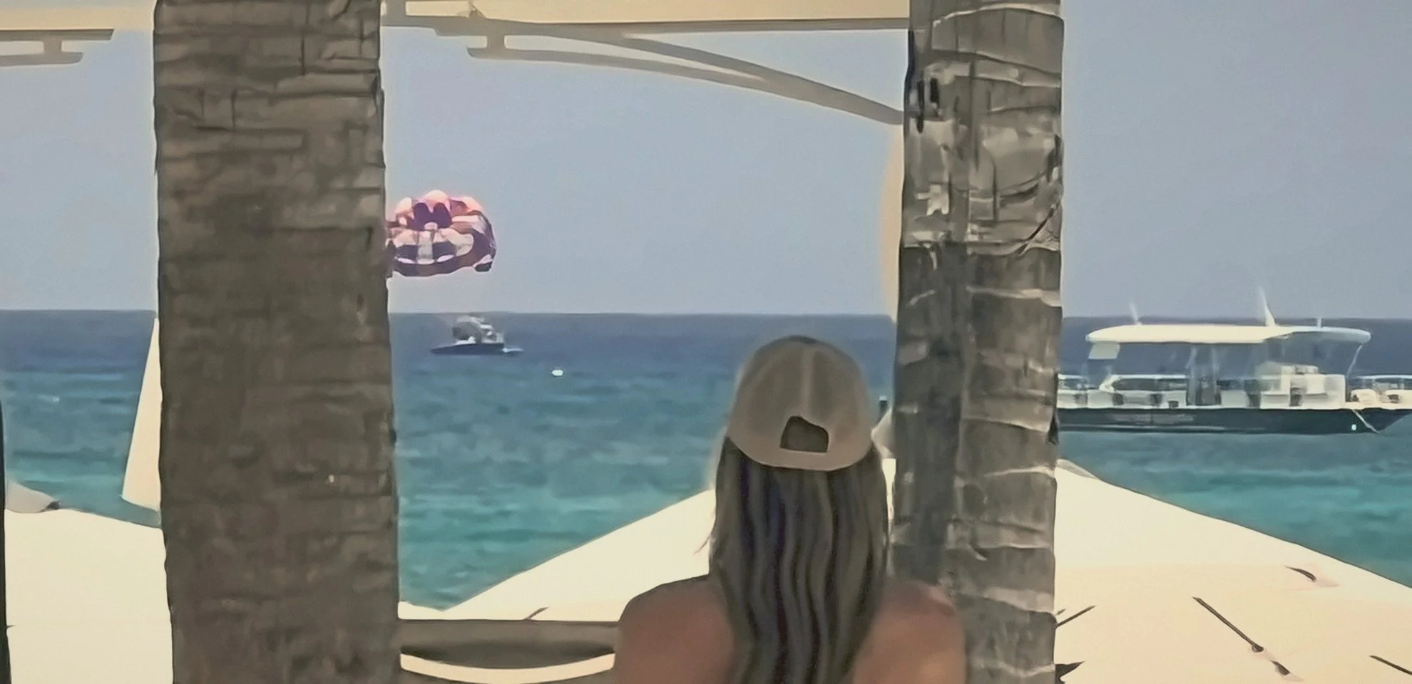 Paige looking out at a turquoise sea between palm trees