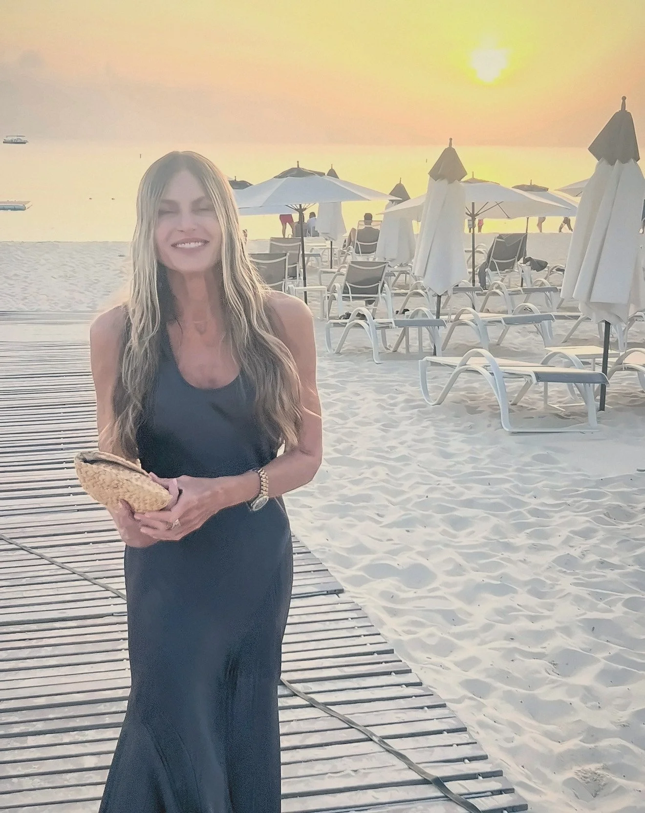 Paige Bronson smiling on a beach boardwalk at golden sunset