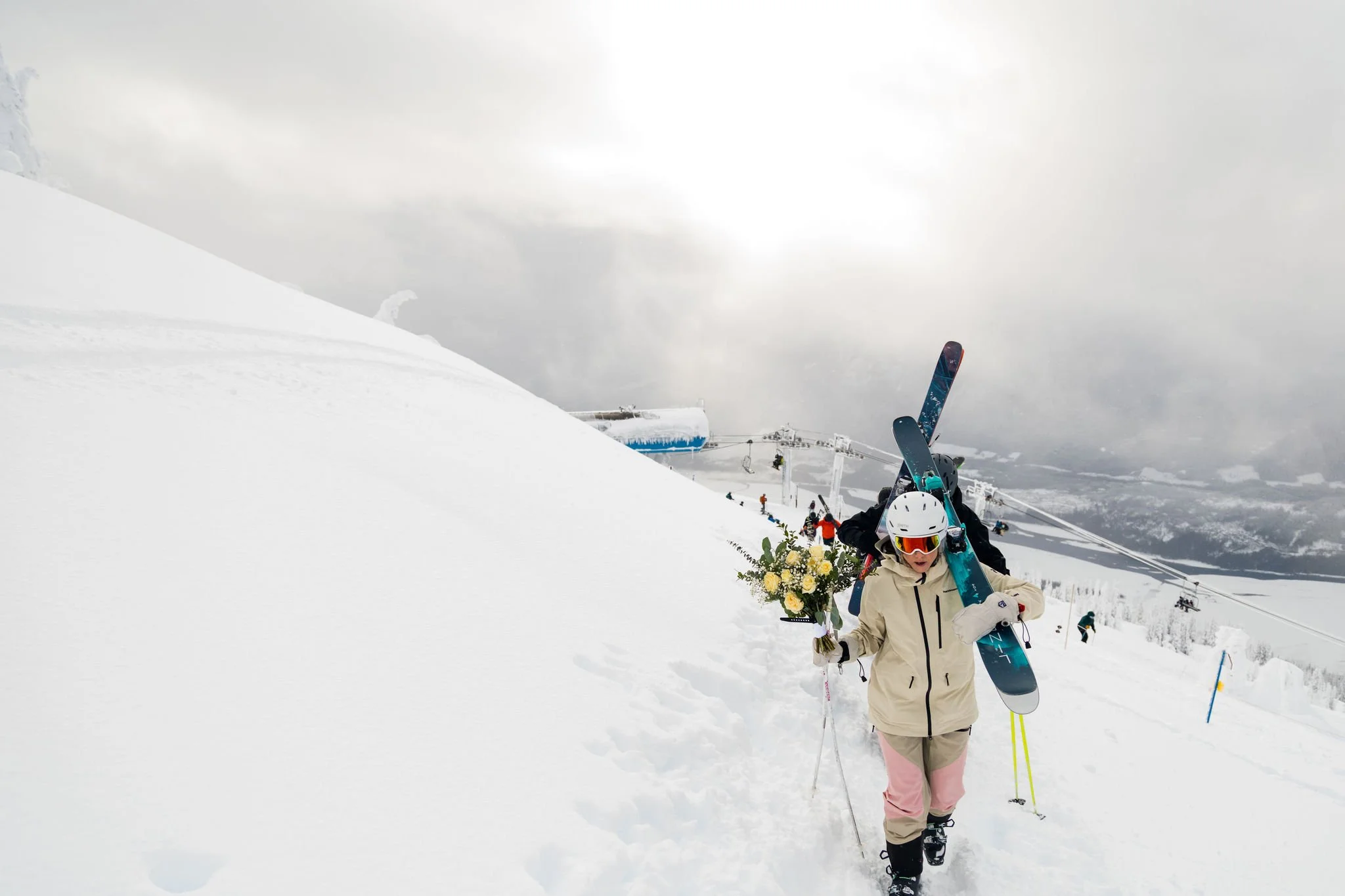 bride holding a bouquet carried skies up a mountain at a ski resort