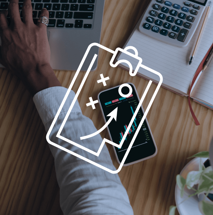 Un bureau avec un ordinateur portable, une calculatrice, un téléphone affichant des graphiques financiers, un carnet de notes, un stylo, et une plante, avec une superposition d'icône représentant une stratégie ou un plan.