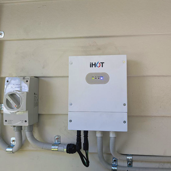 Electrical box labeled 'iHOT' mounted on a wall with status lights, and another smaller electrical component to the left with wiring.