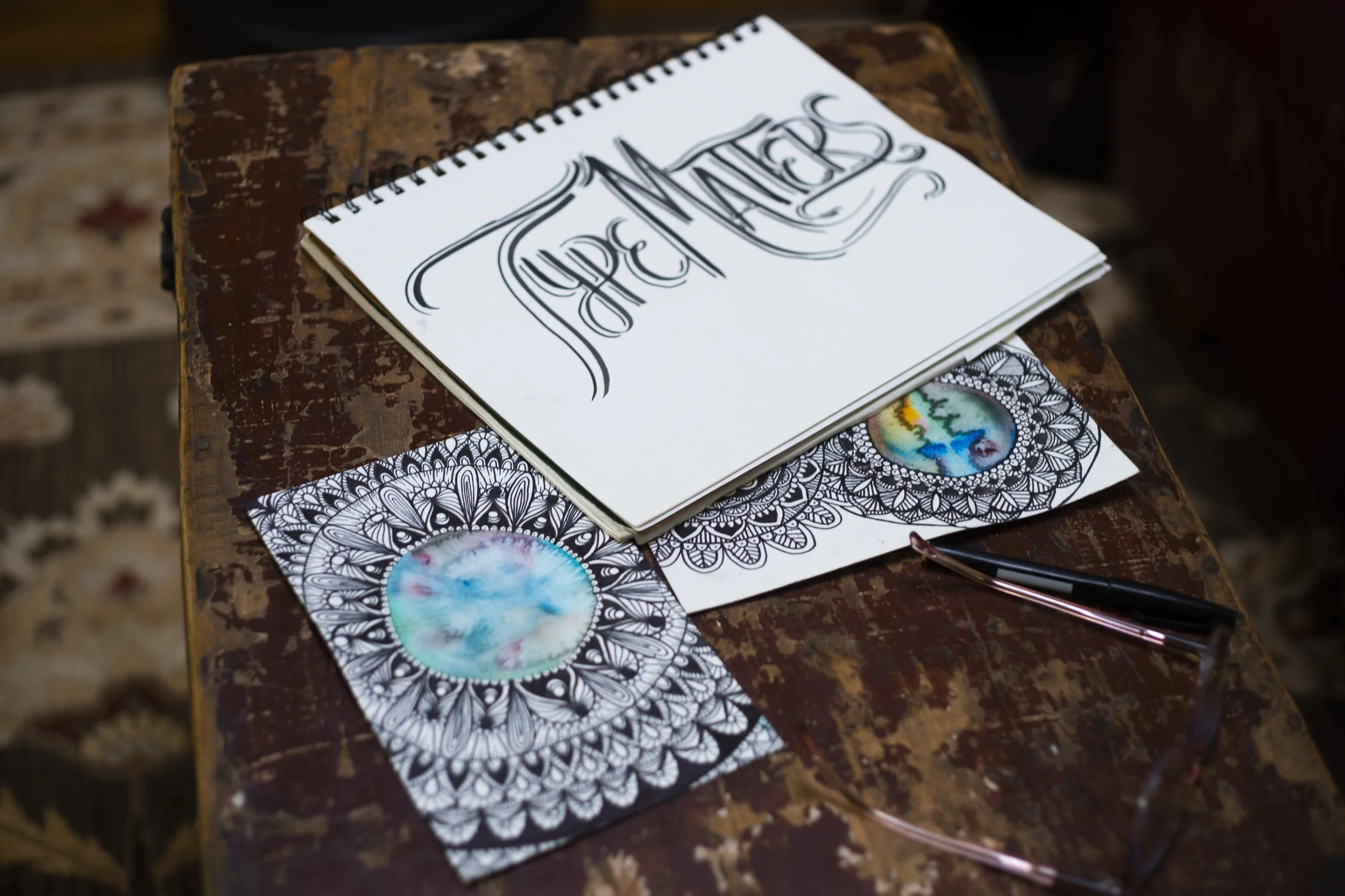 Two Watercolor mandala moons created by Chelsea Willett and hand drawn type in a sketchbook.