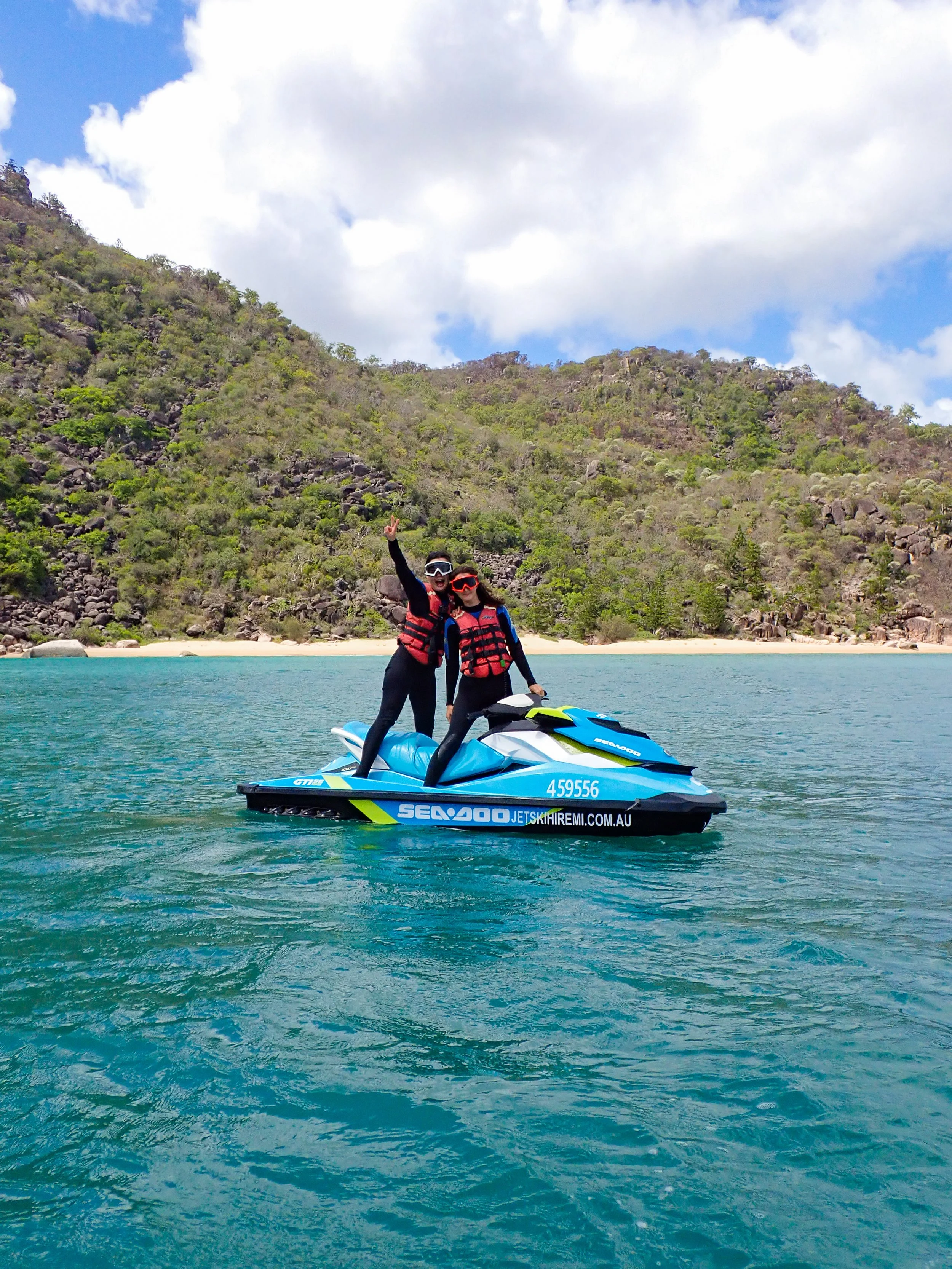 A couple on a jet ski having a photo in Five Beach Bay in front of a secluded beach.