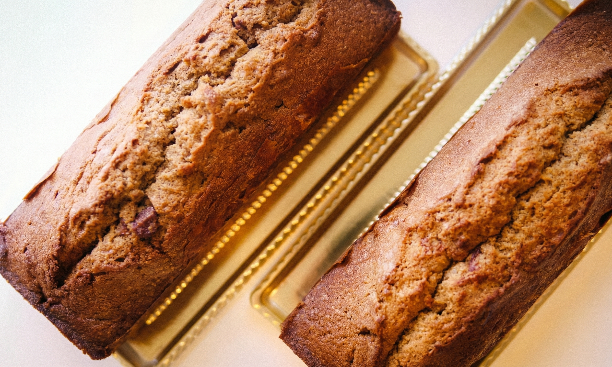 黄金色のトレイに並んだパウンドケーキ。自家製ヘーゼルナッツペーストを使用した温かみのある質感で、生徒の好みに合わせてアレンジされた優しさが伝わる写真。