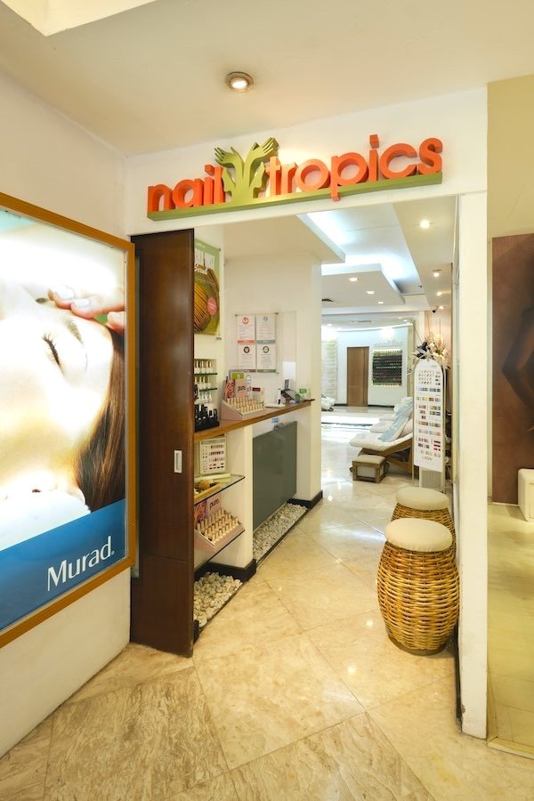 Entrance to a salon named Nail Tropics with chairs and decor inside.