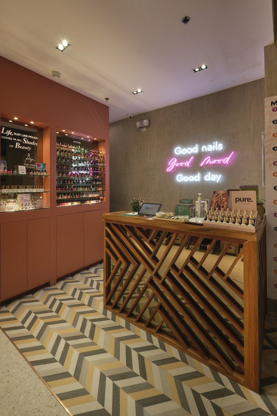 Nail salon interior with colorful nail polish display, wooden reception desk, and a neon sign reading "Good nails, good mood, good day."