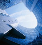 Looking up at a modern office building's curved glass facade with surrounding skyscrapers