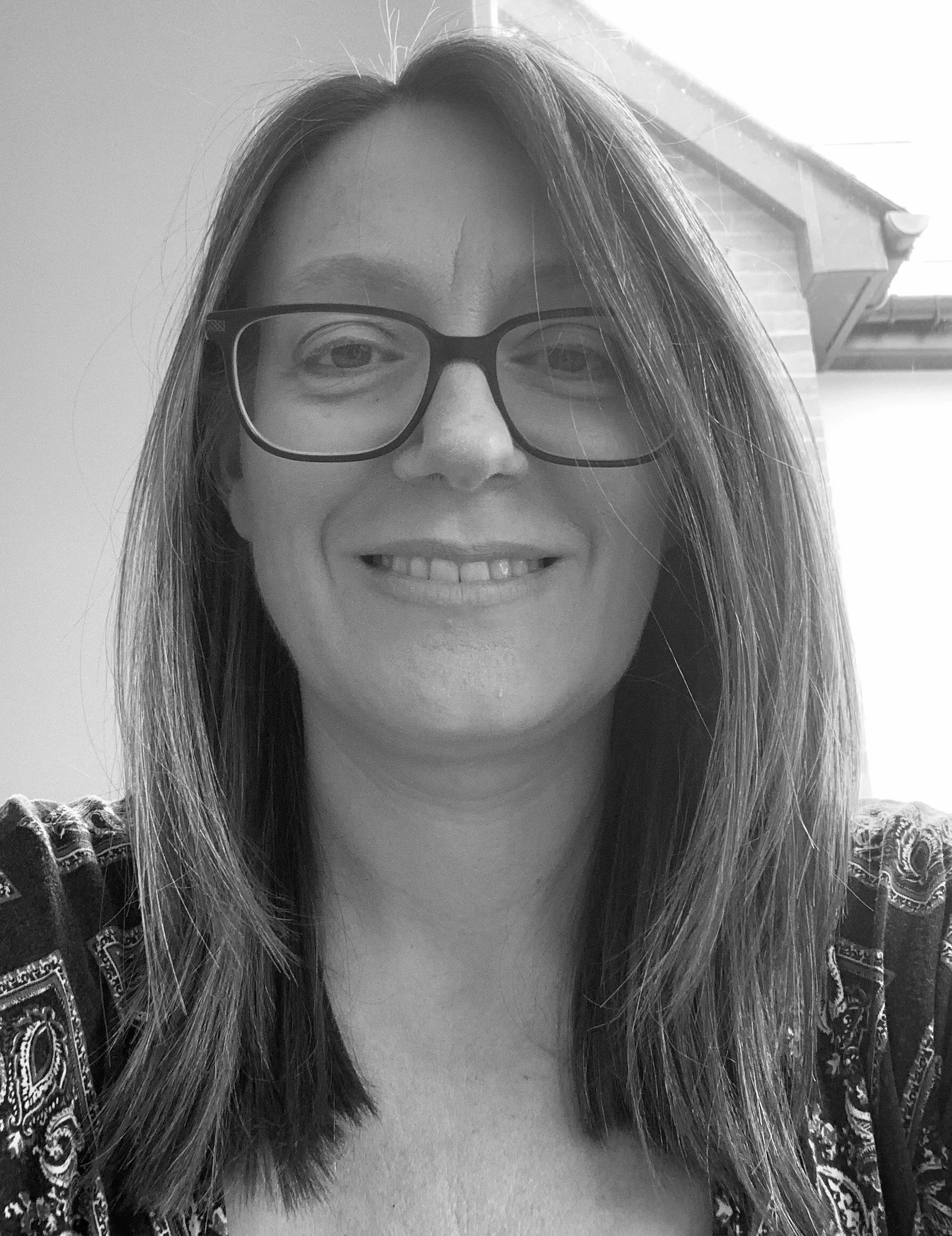 Black and white head shot of a woman with long hair and glasses