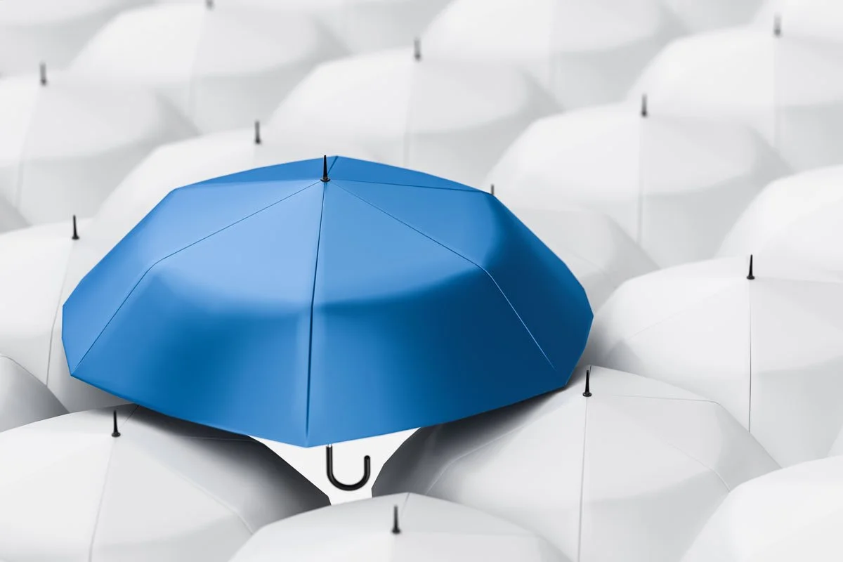 Group of white umbrellas with a blue one on top