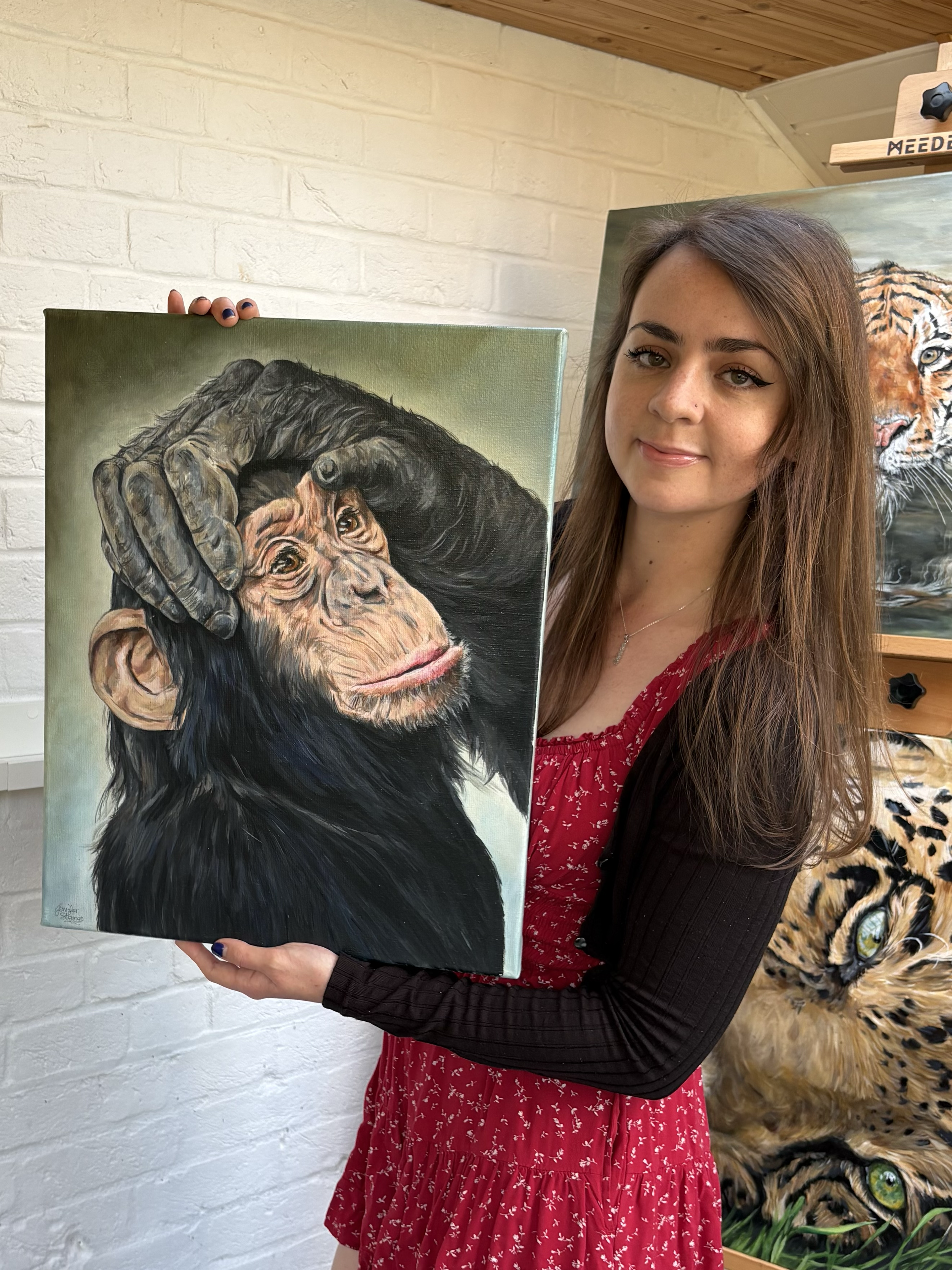 artist holds a painting of a young chimp