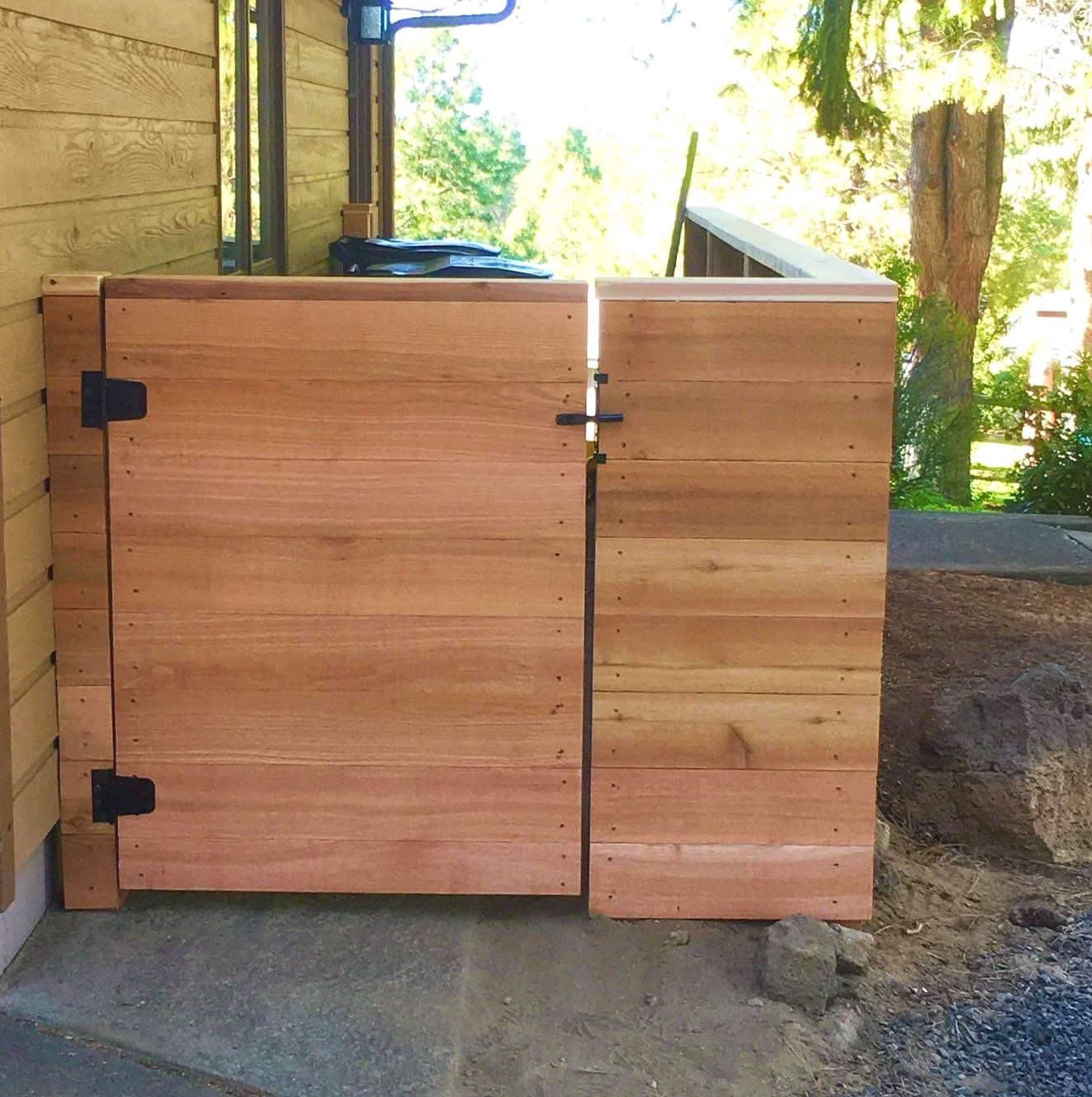 Wooden fence enclosure with black hinges on a patio, outdoor setting