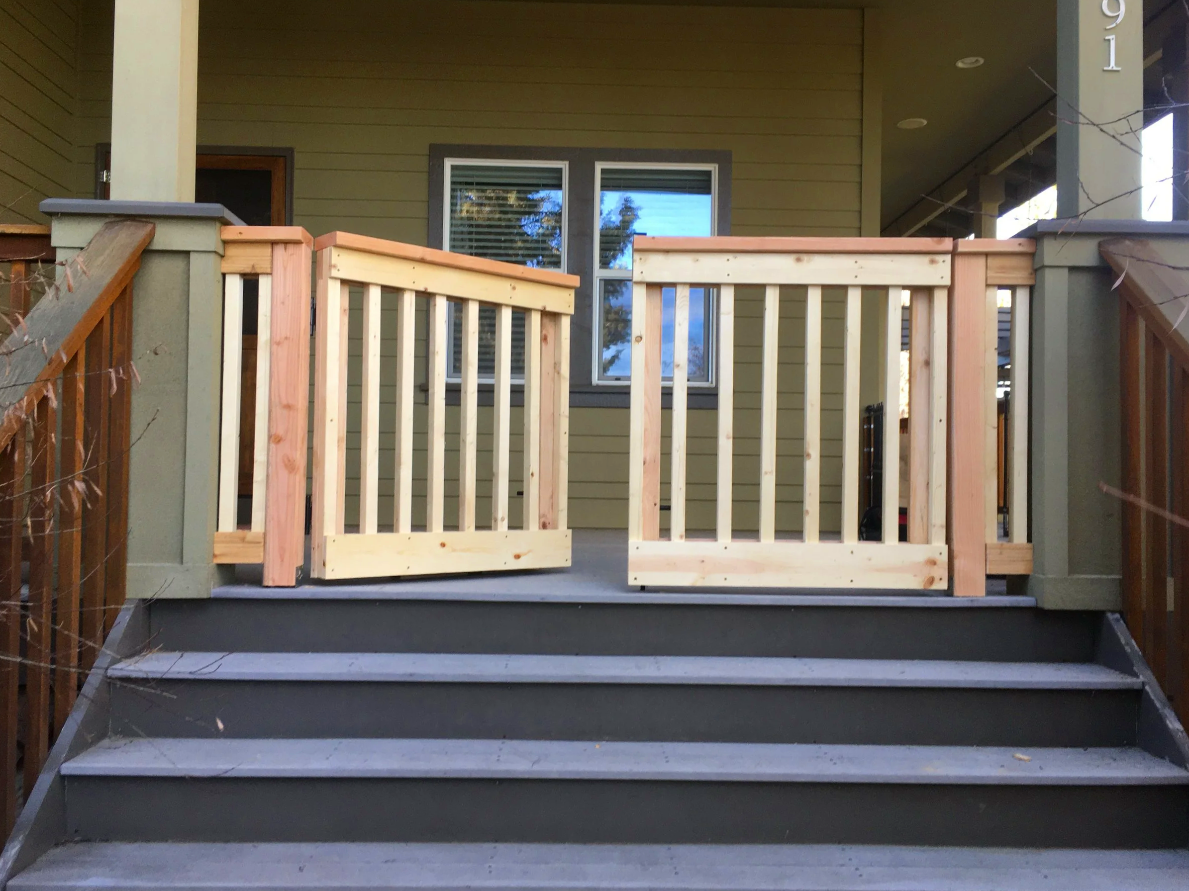 Wooden safety gates installed at the top of exterior porch stairs.