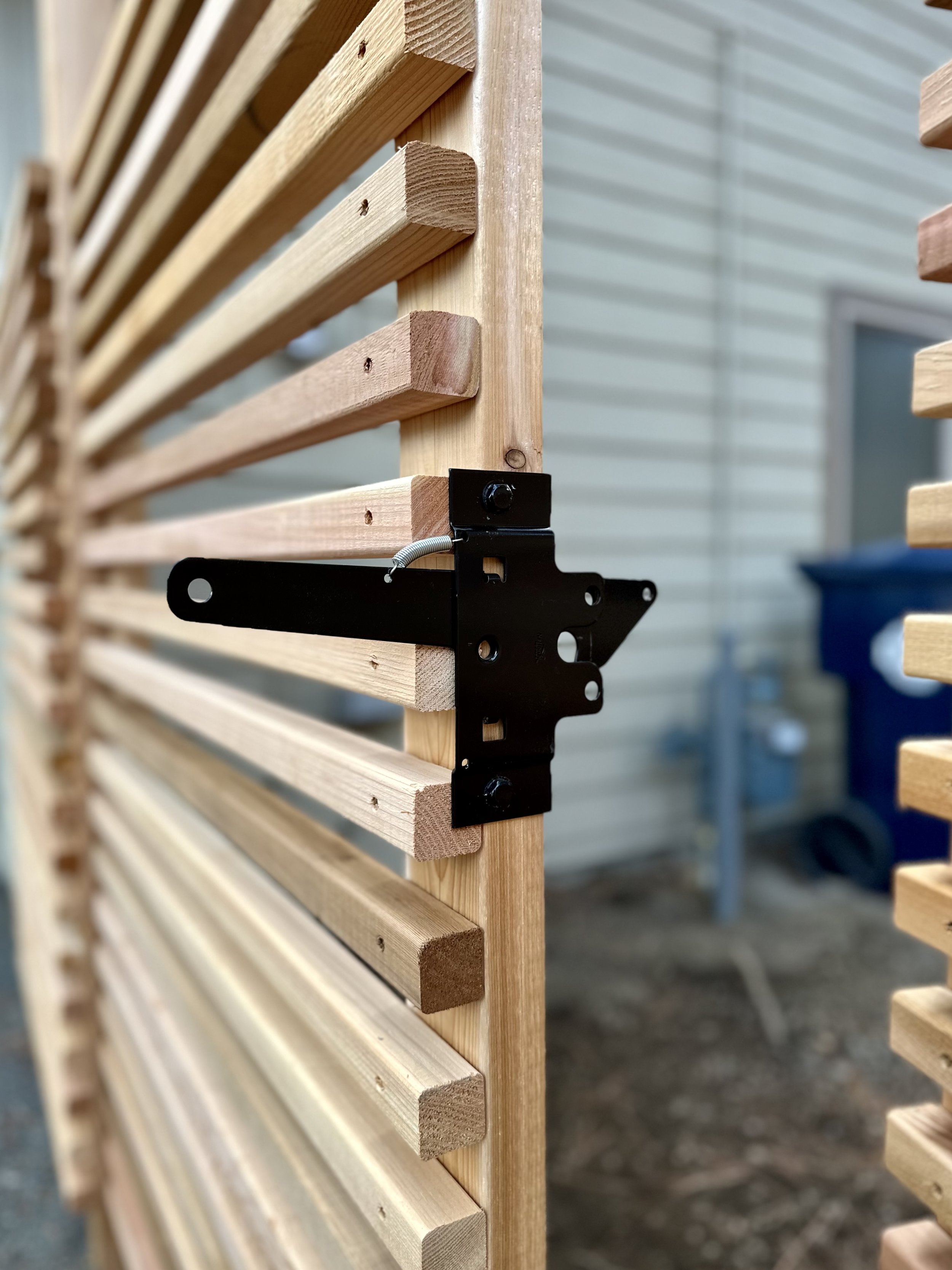 Close-up of a wooden slat structure being assembled with a black metal bracket and screw.