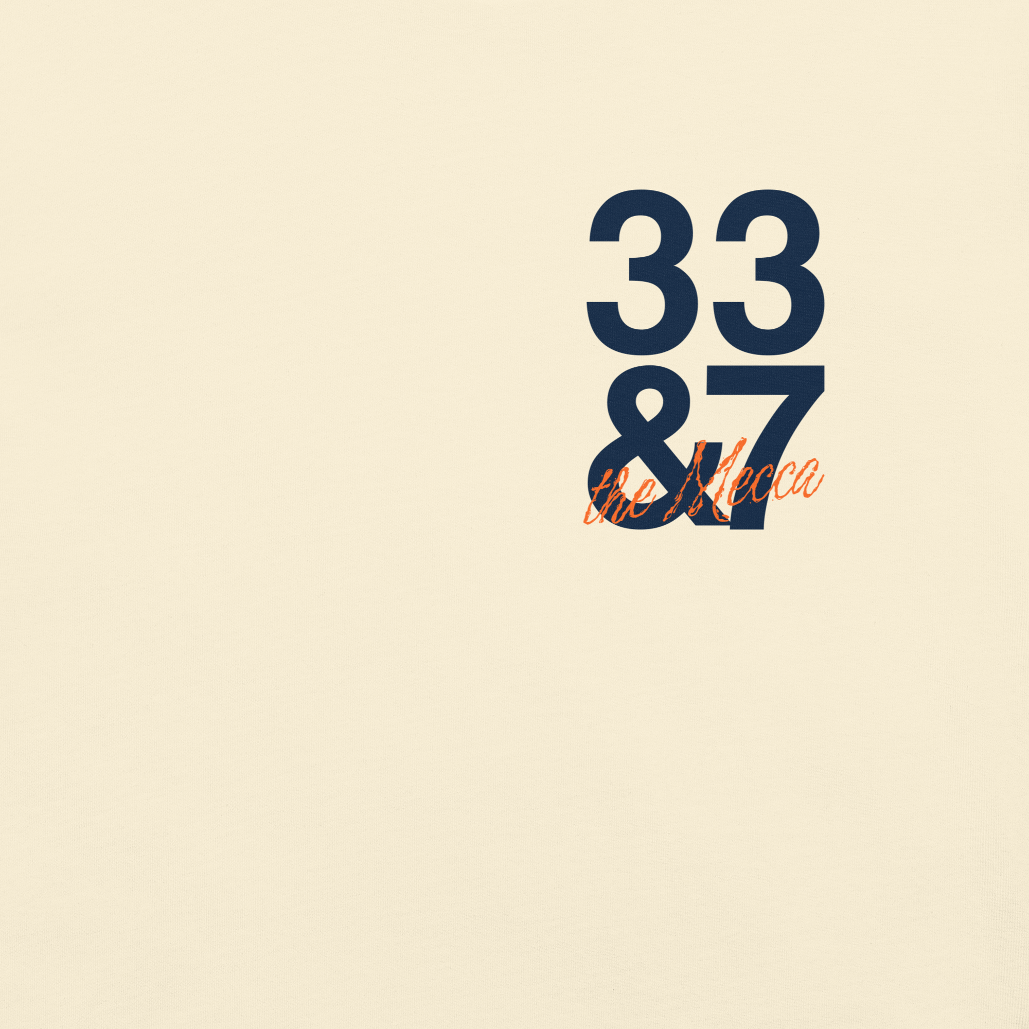 Cream Comfort Colors t-shirt with a small "33 & 7" chest print in deep navy block numerals, with "the Mecca" in orange handwritten script below.
