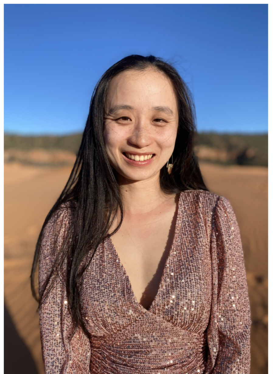 Yunzhe Zhou, business coach for Asian women, smiling standing in an outdoors landscape with a blue sky.