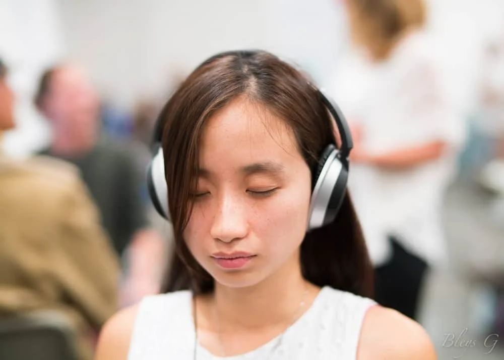 Yunzhe Zhou during her marketing career in San Francisco, wearing headphones with eyes closed, finding a moment of quiet focus in a busy indoor space.
