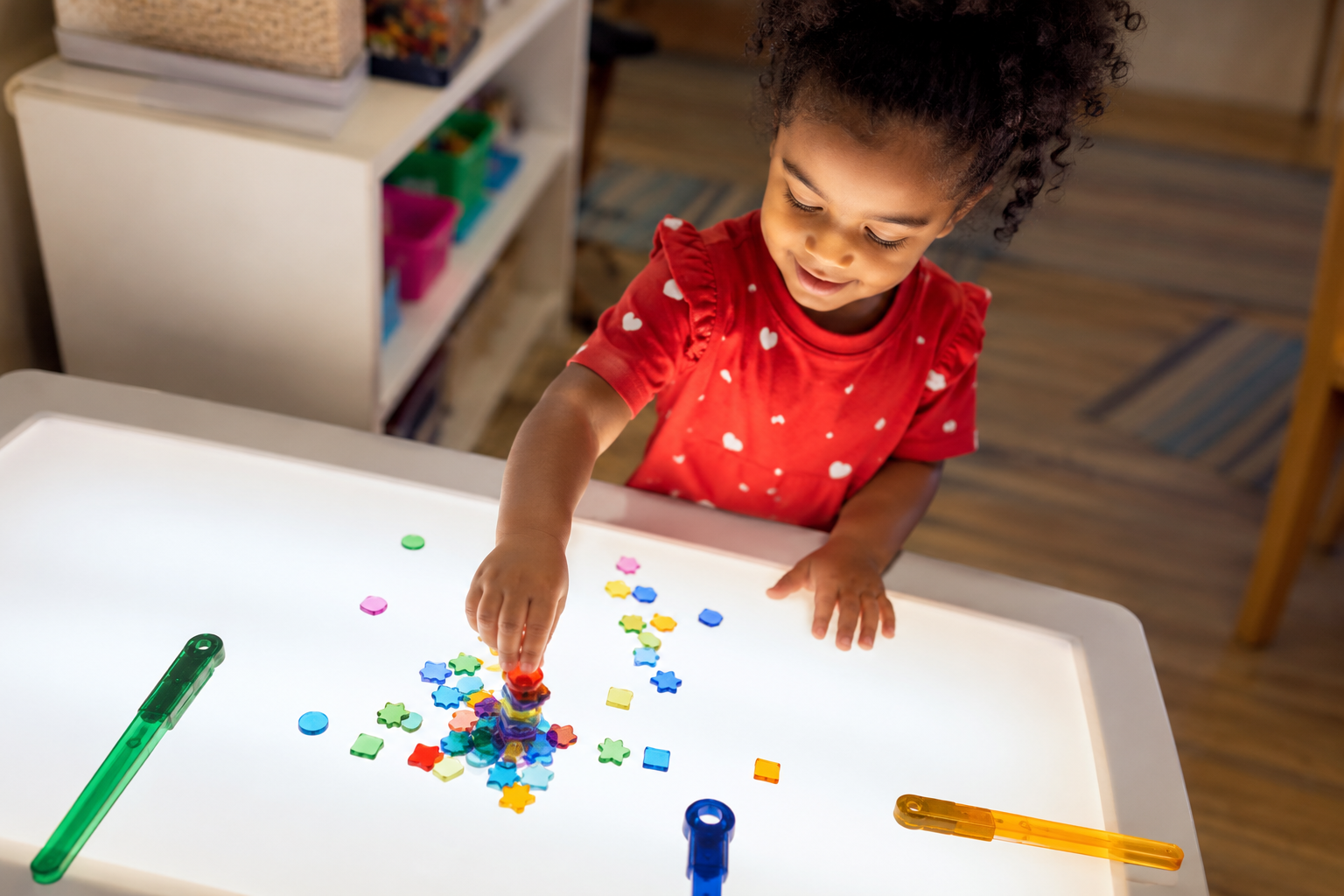WHPS preschool student exploring colorful materials at a light table