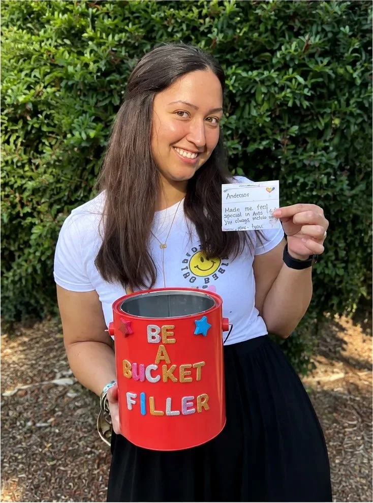WHPS teacher holding a Be a Bucket Filler bucket and recognition note