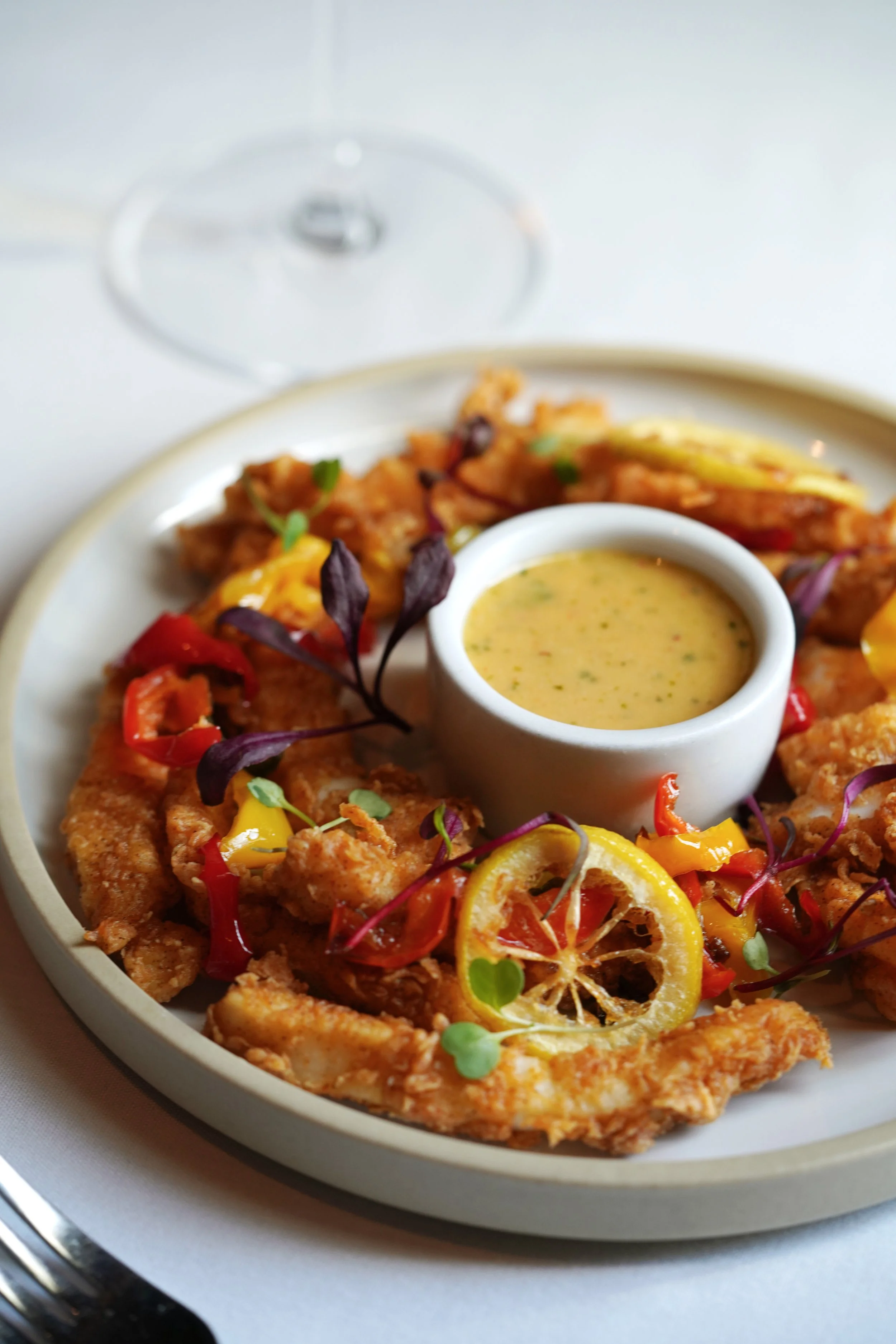 A plate of fried fish with lemon slices, vegetables, and dipping sauce at level 2 fine dining steakhouse in branson missouri