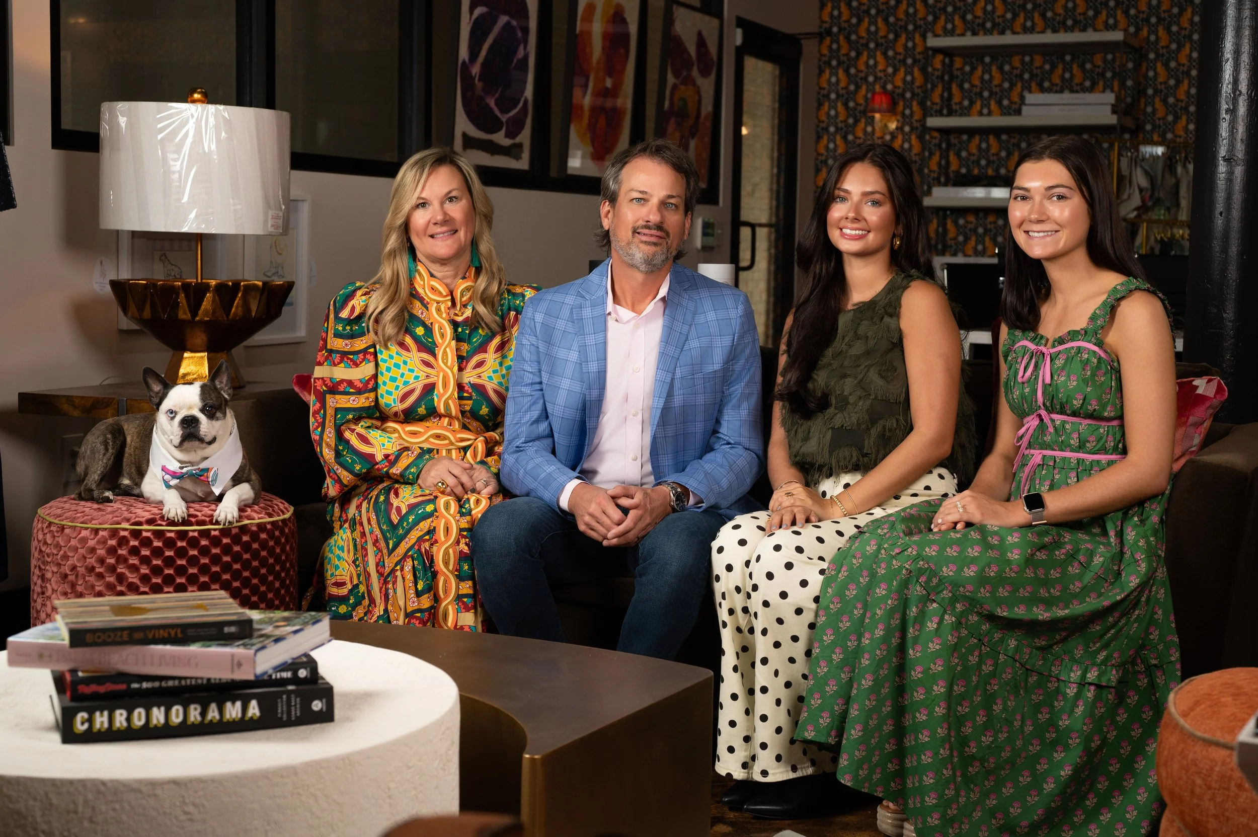 A group of five people and a dog sitting on a sofa in a cozy, well-decorated living room. studio headshot business
