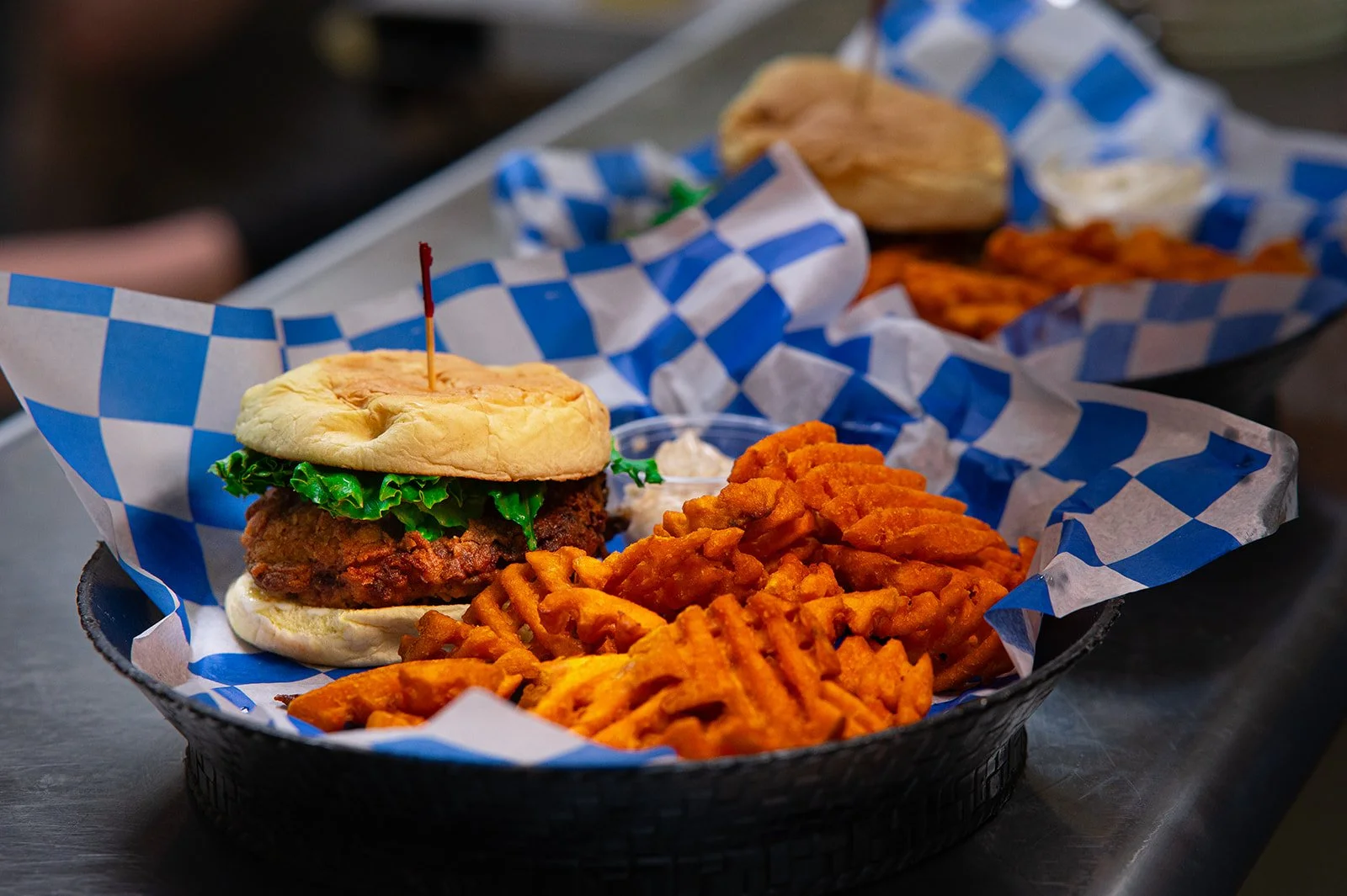 A basket with a fried chicken sandwich and seasoned waffle fries.