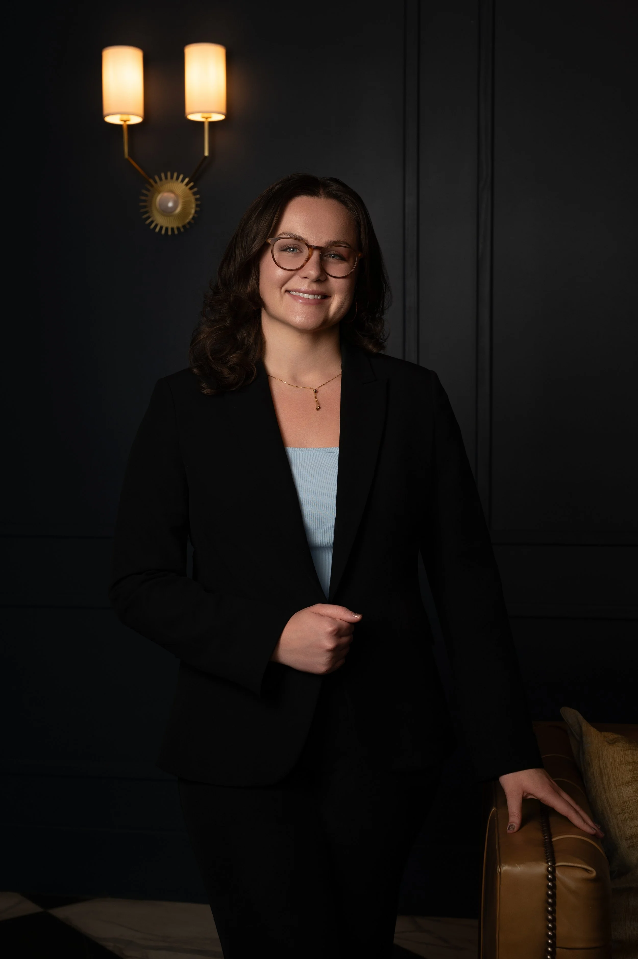 A woman with shoulder-length brown hair, headshot lights behind her. business