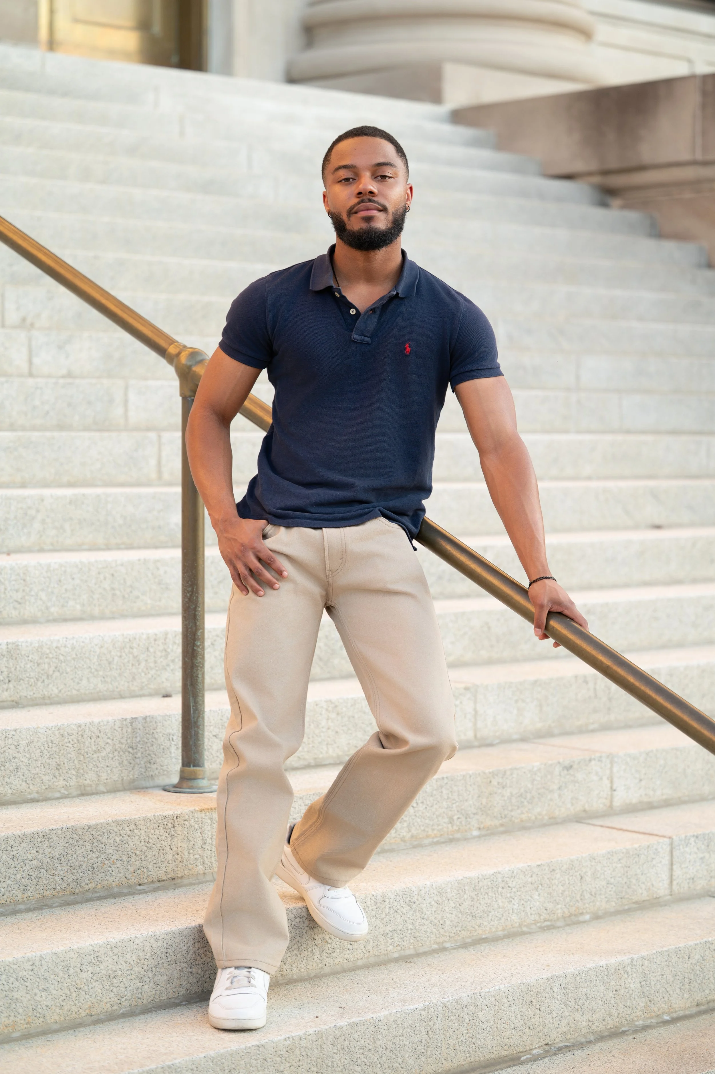 Outdoor portrait session of a man on grand stone steps, casual outfit.